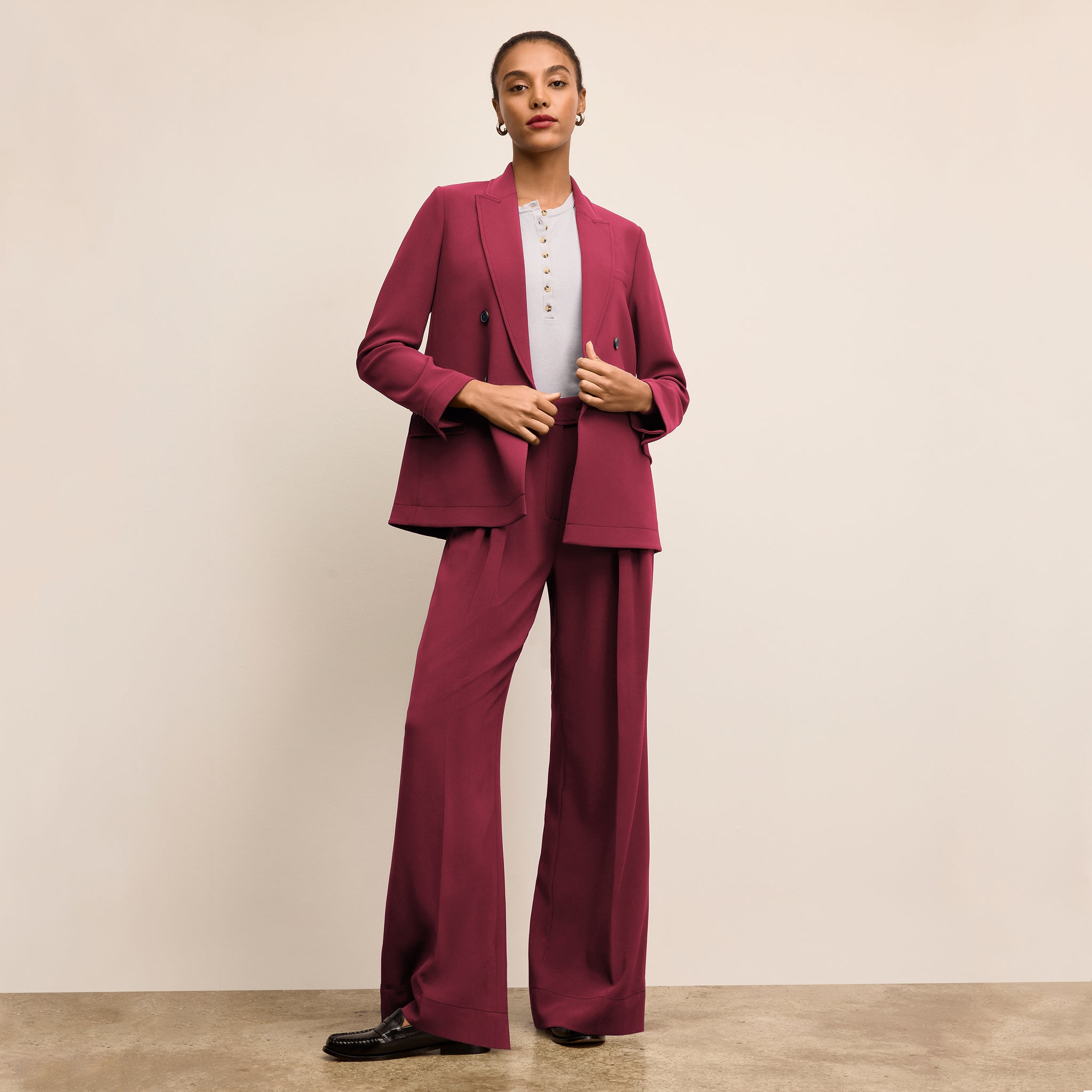 Woman wearing a burgundy suit standing against a beige background