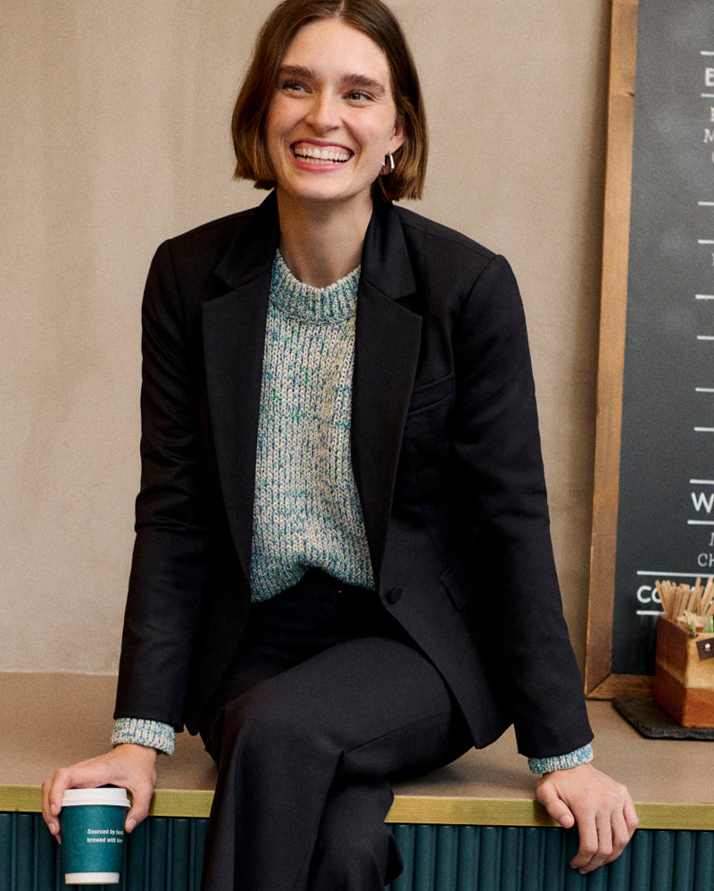 Image of a woman wearing a black suit sitting on counter