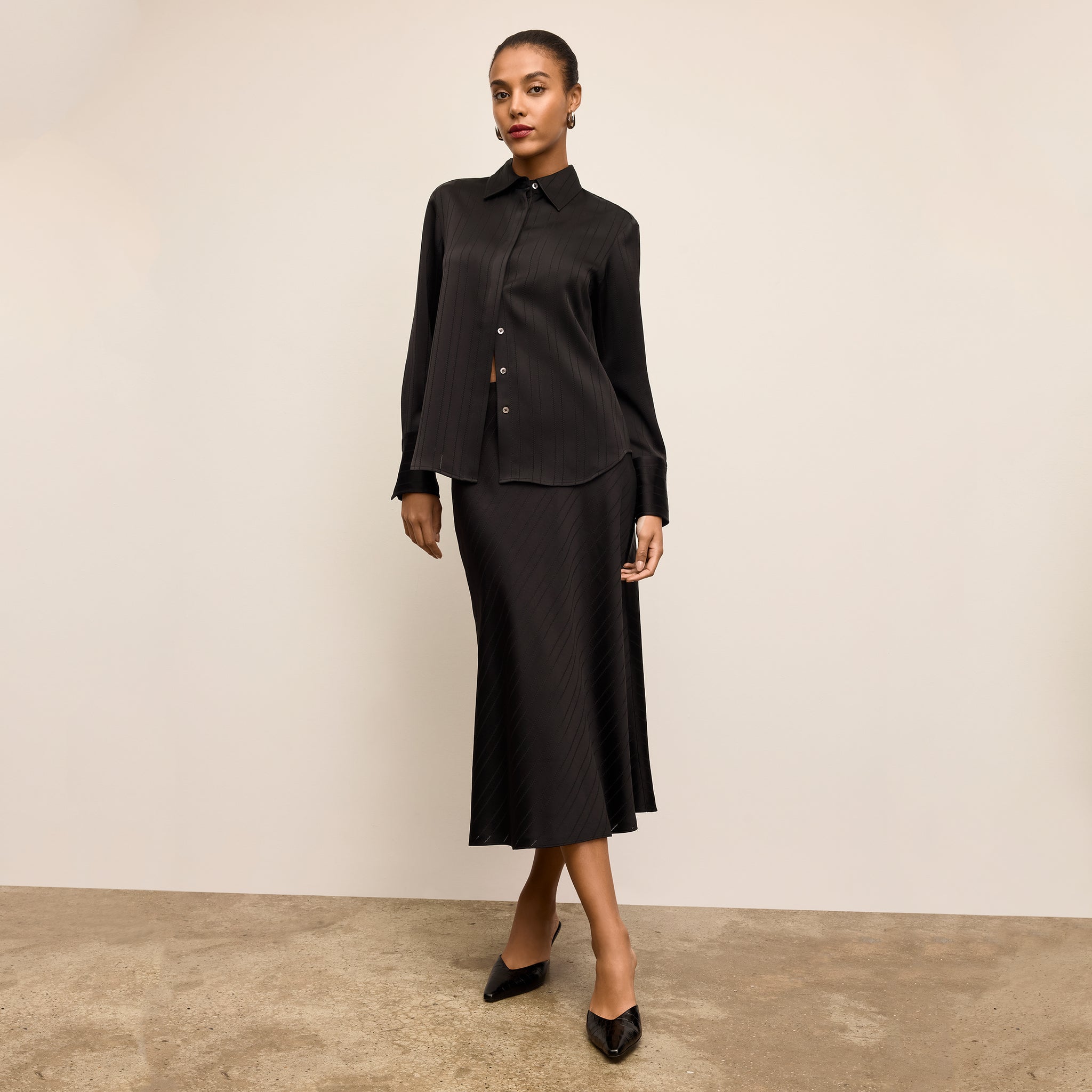 Woman wearing a black outfit against a beige background