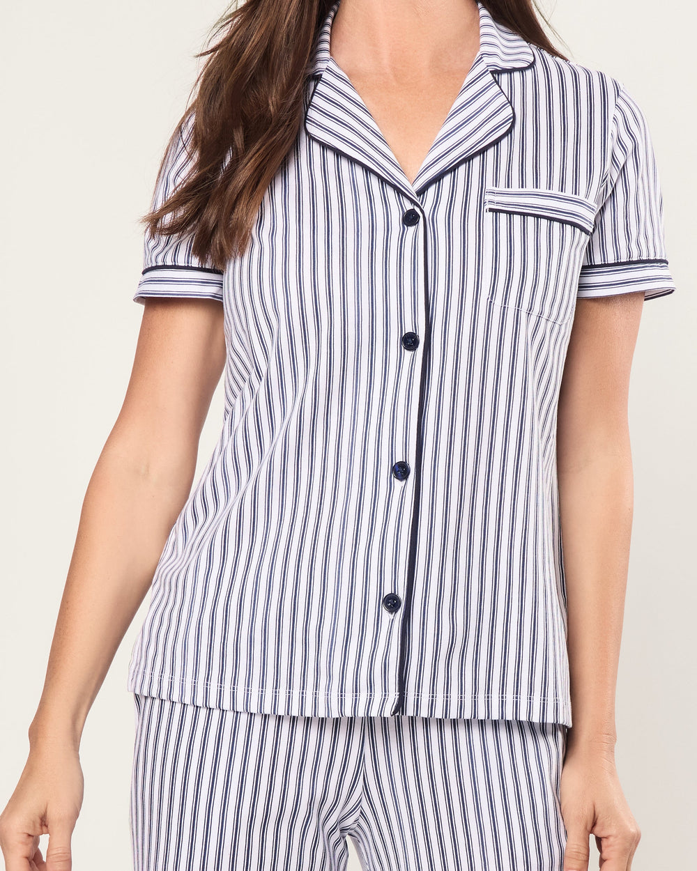 Woman wearing a black and white striped pajama set on a plain background