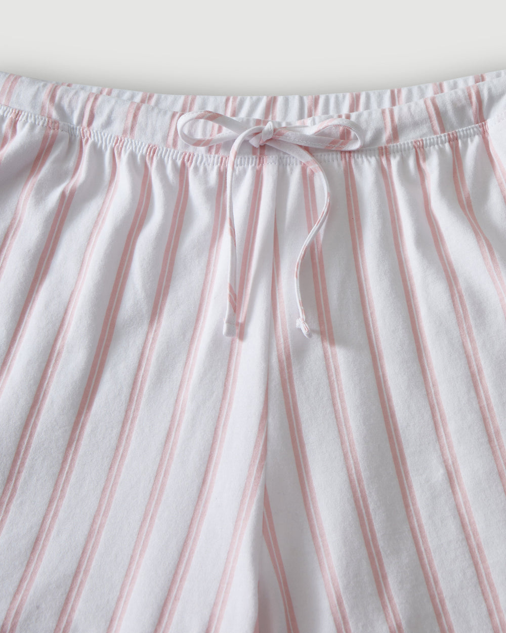 Close-up of striped pajama pants with a drawstring waistband on a light background.