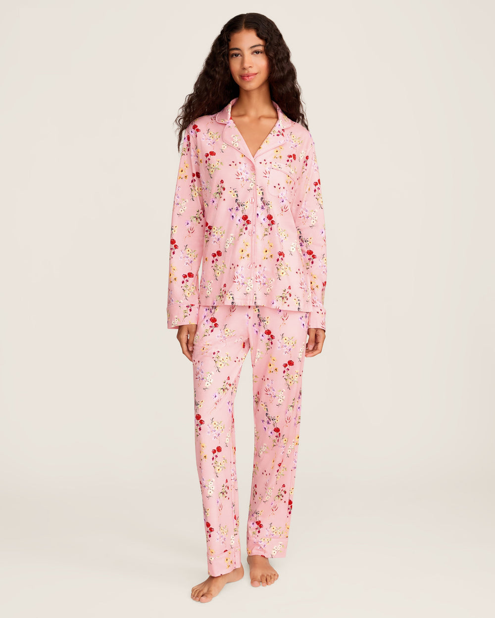 Woman wearing a pink floral pajama set on a white background