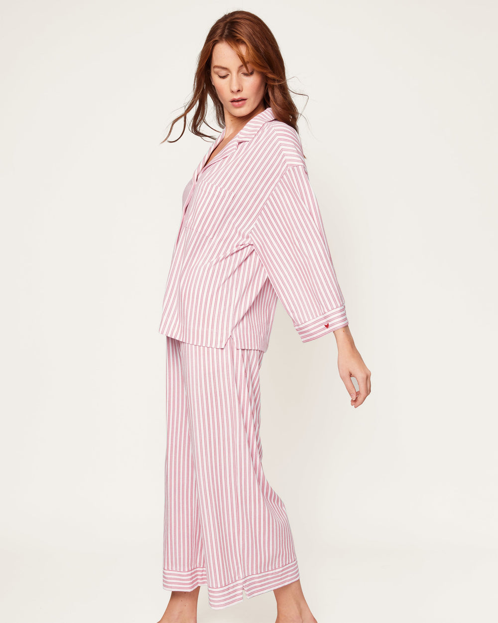 Woman wearing a pink and white striped pajama set on a light background