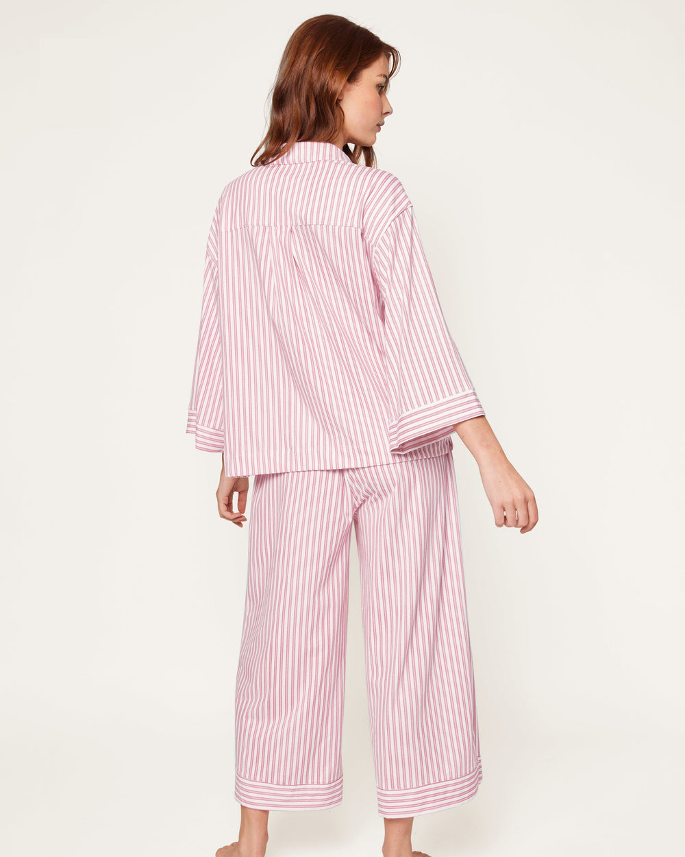 Woman wearing a pink and white striped pajama set on a white background
