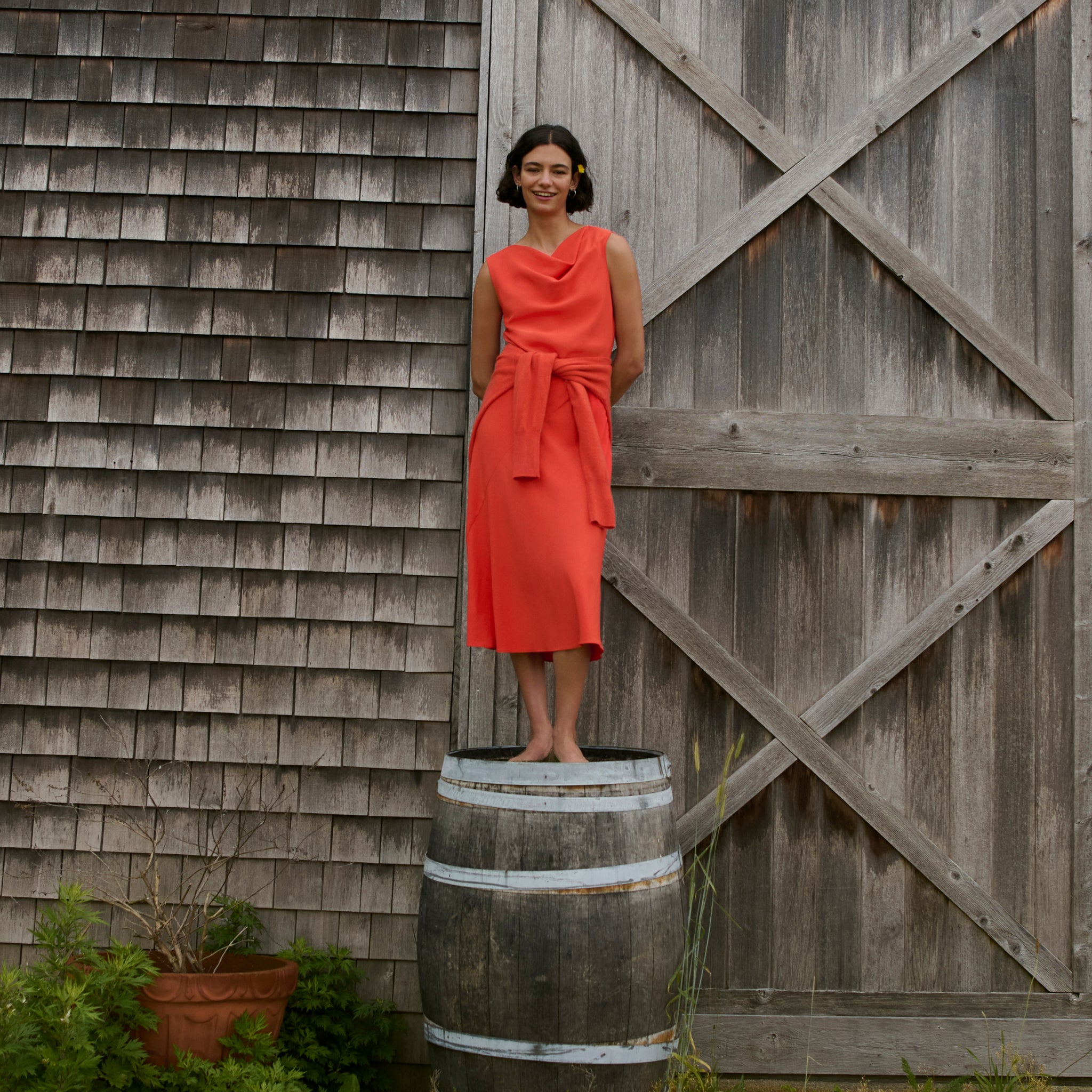 image of a woman wearing the priya dress in bright coral