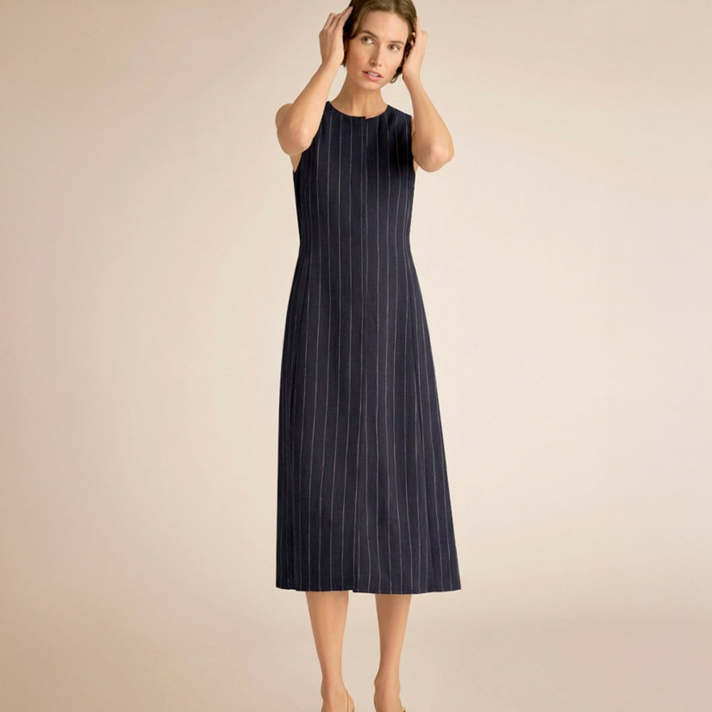 Woman wearing a navy pinstripe dress against a beige background.