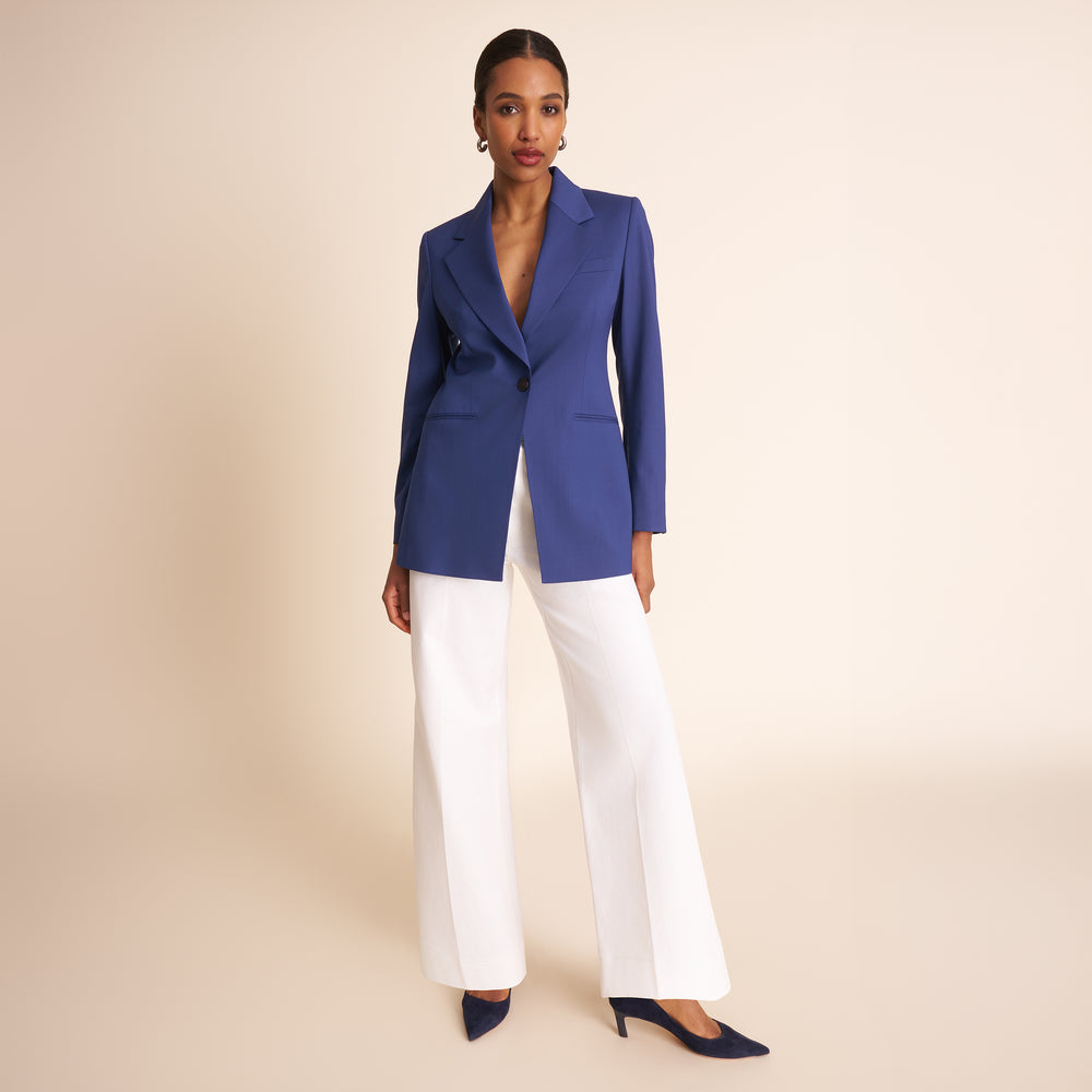 Woman wearing a blue suit with a white top on a beige background