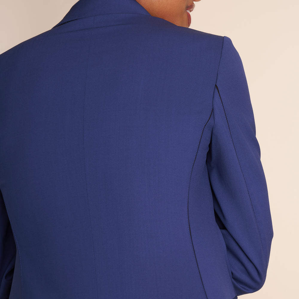 Woman wearing a blue suit with a white top on a beige background