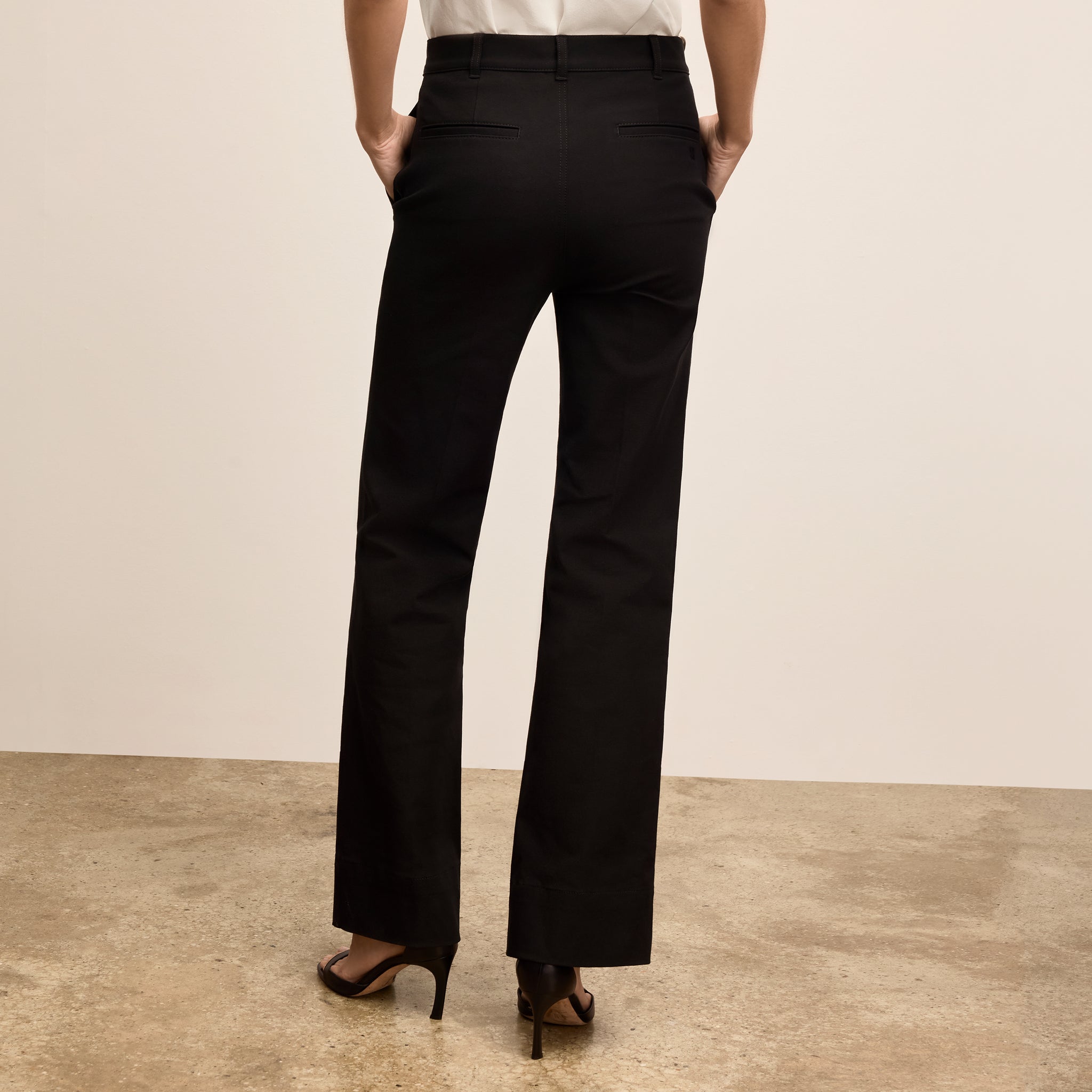 Person wearing black pants on a beige background