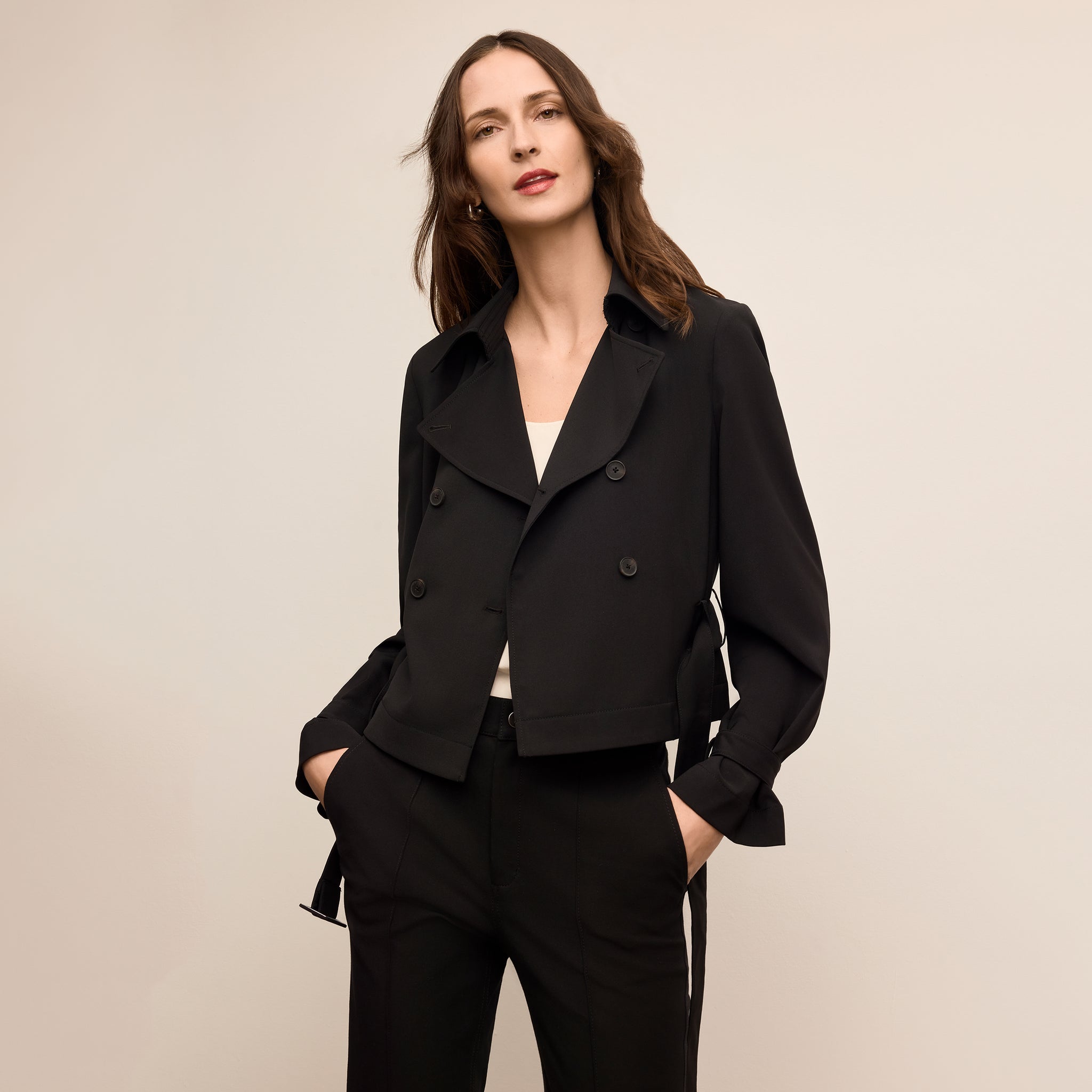 Woman wearing a black suit against a beige background 