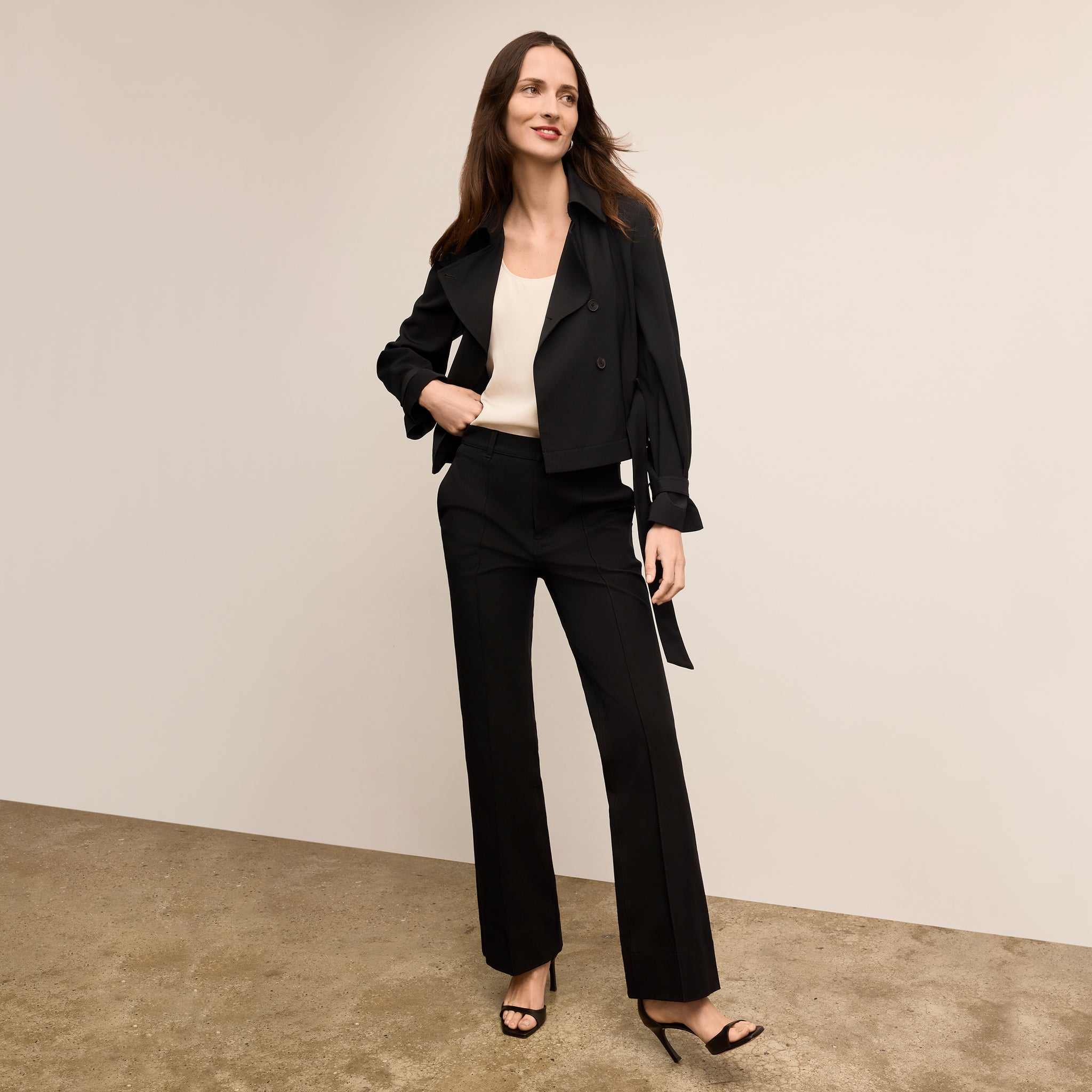Woman wearing a black suit standing against a plain background