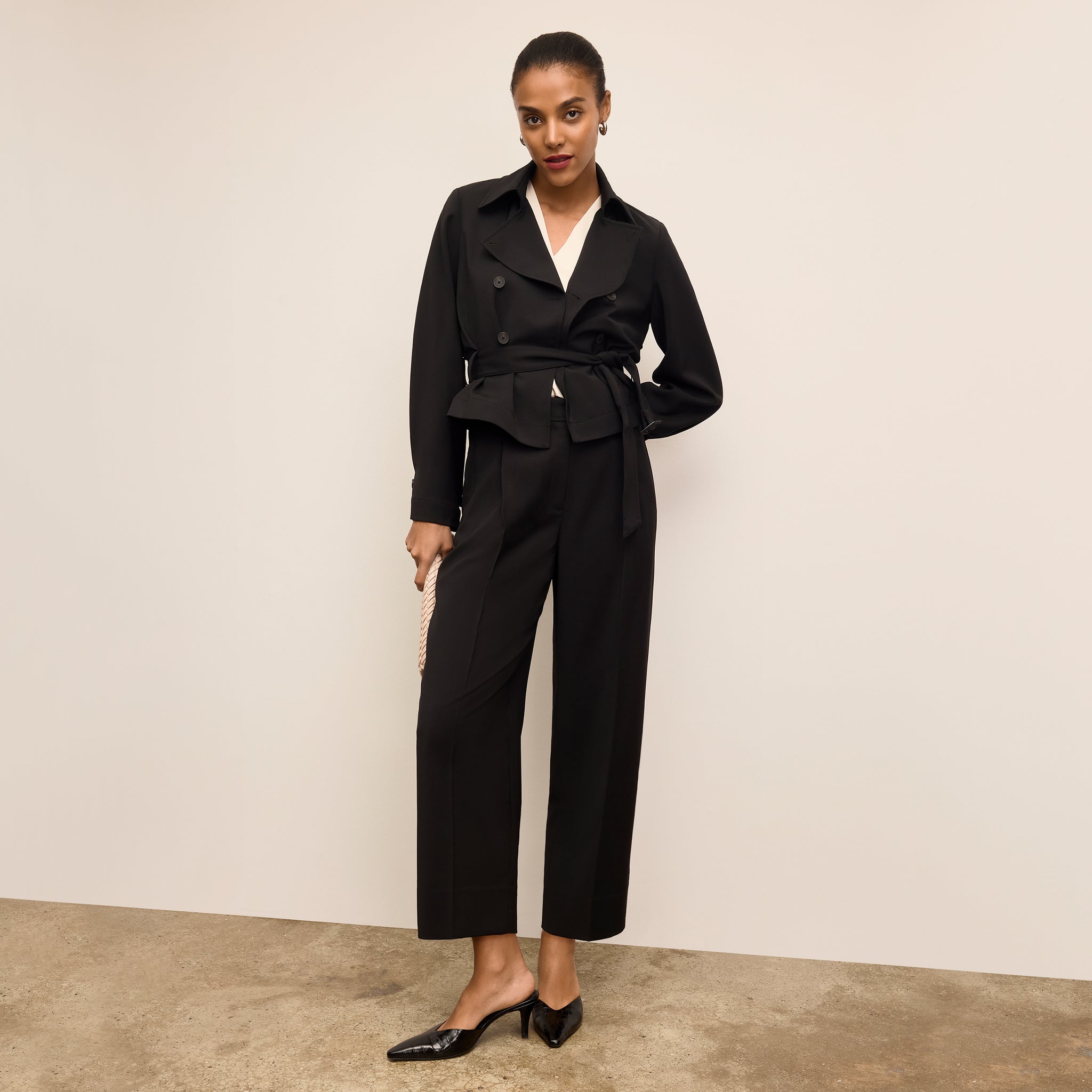 Woman wearing a black suit with a white shirt against a beige background