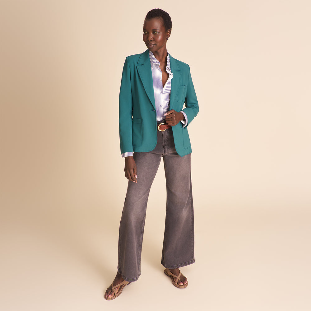Woman wearing a teal suit against a beige background