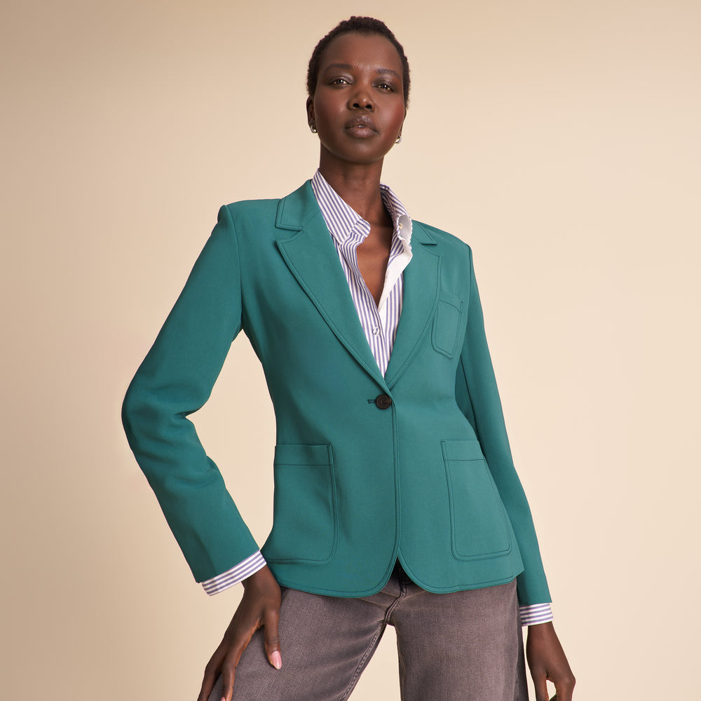 Woman wearing a teal suit against a beige background