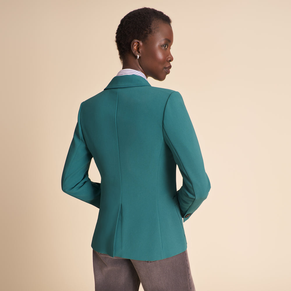 Woman wearing a teal suit against a beige background