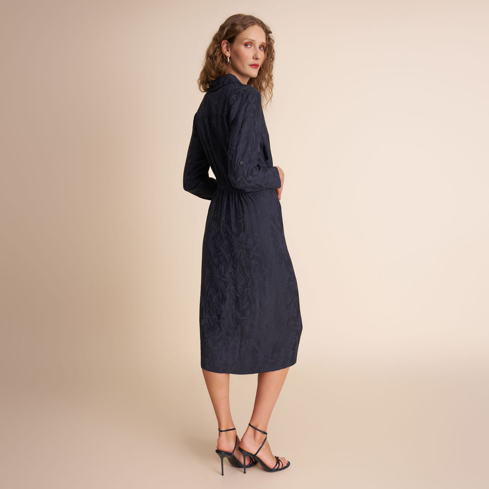 Woman wearing a navy dress against a beige background