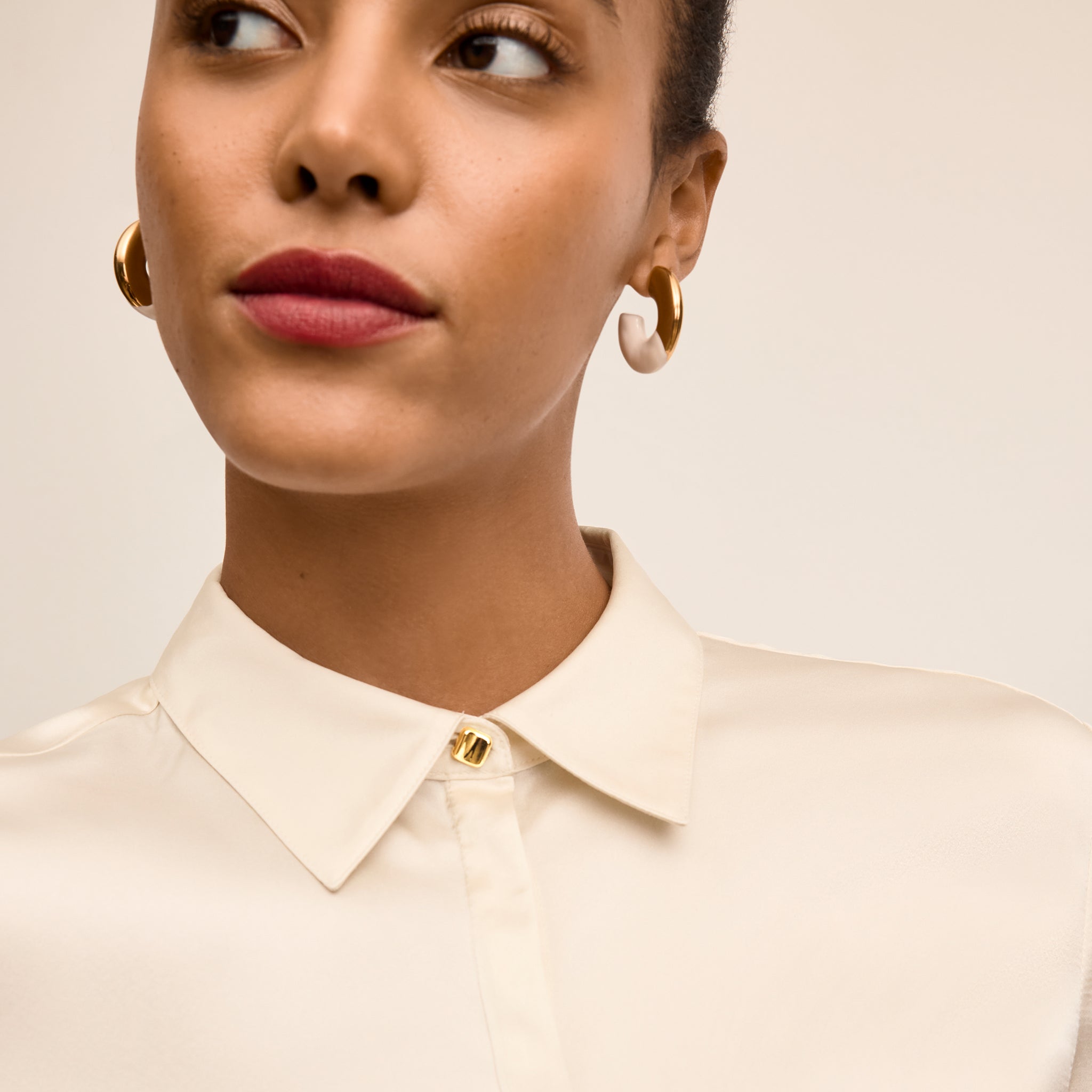 Woman wearing a beige shirt with a plain background