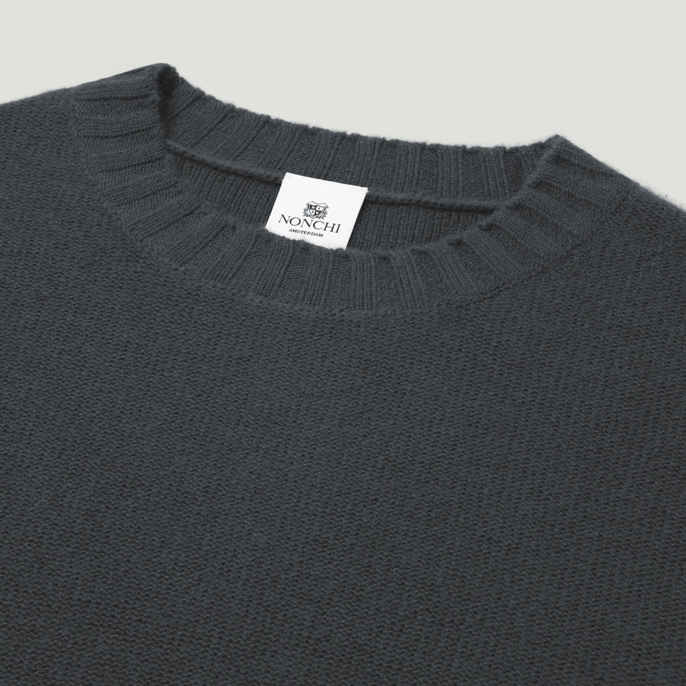 Dark gray sweater with a brand label on a light gray background