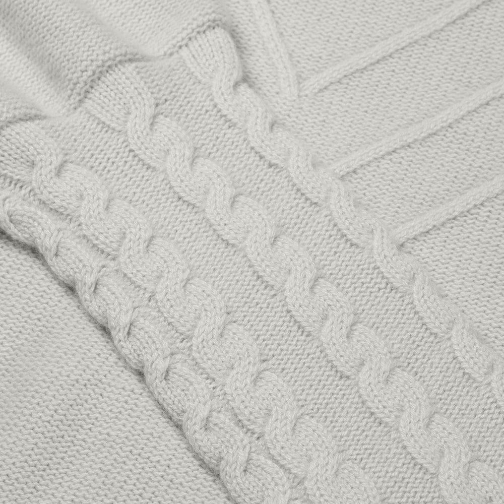 Close-up of a cable knit sweater with a soft gray color.