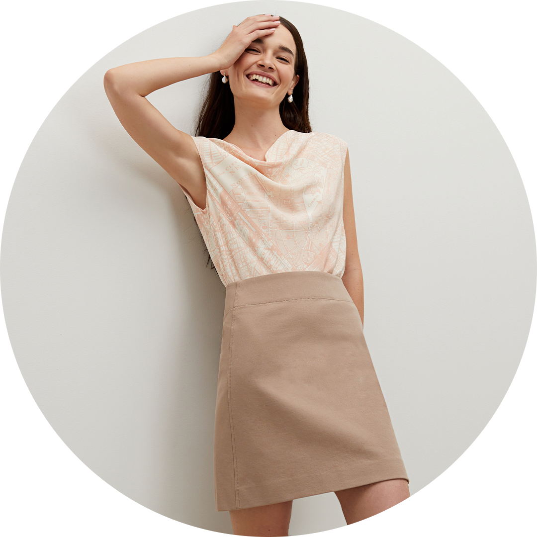 Woman wearing a sleeveless top and beige skirt on a white background