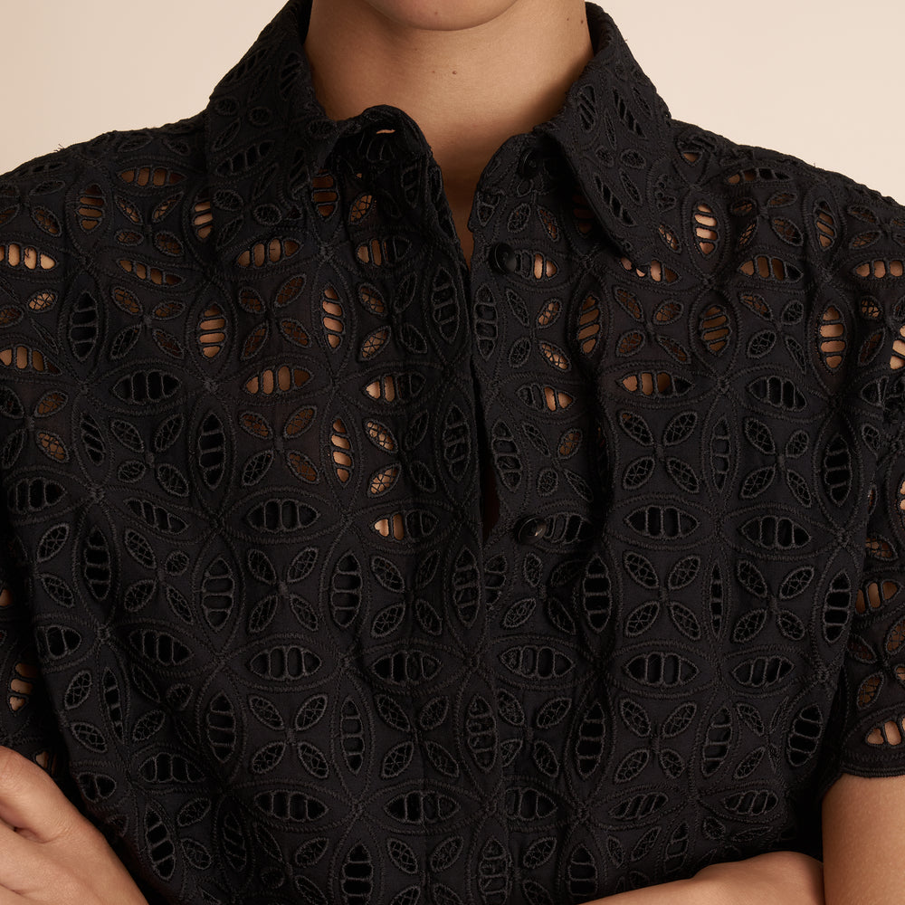 Black lace top worn by a person on a beige background