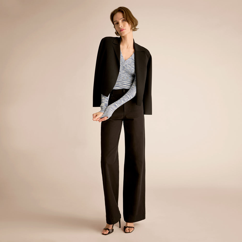 Woman wearing a black suit with a striped top on a beige background