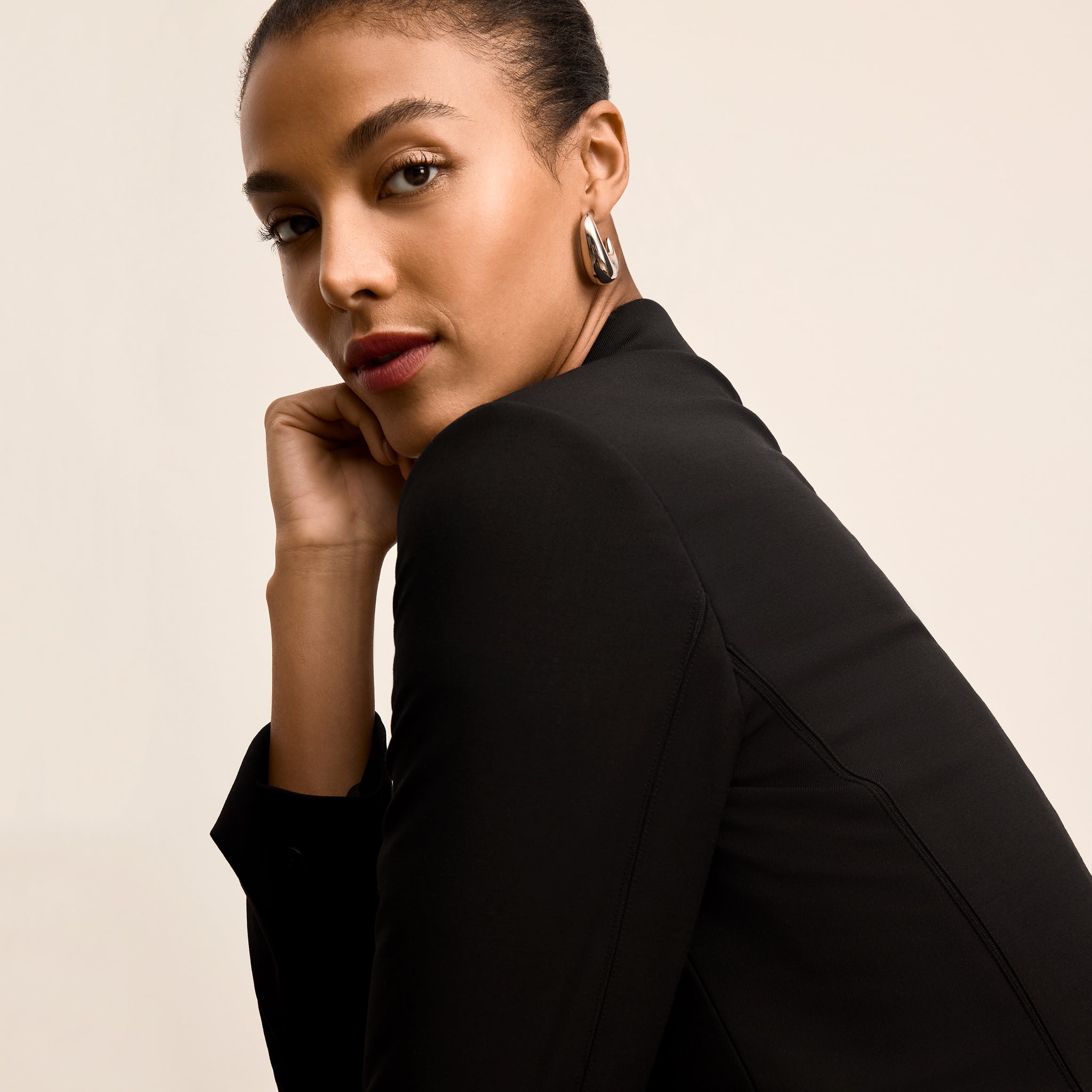 Woman wearing a black blazer against a beige background