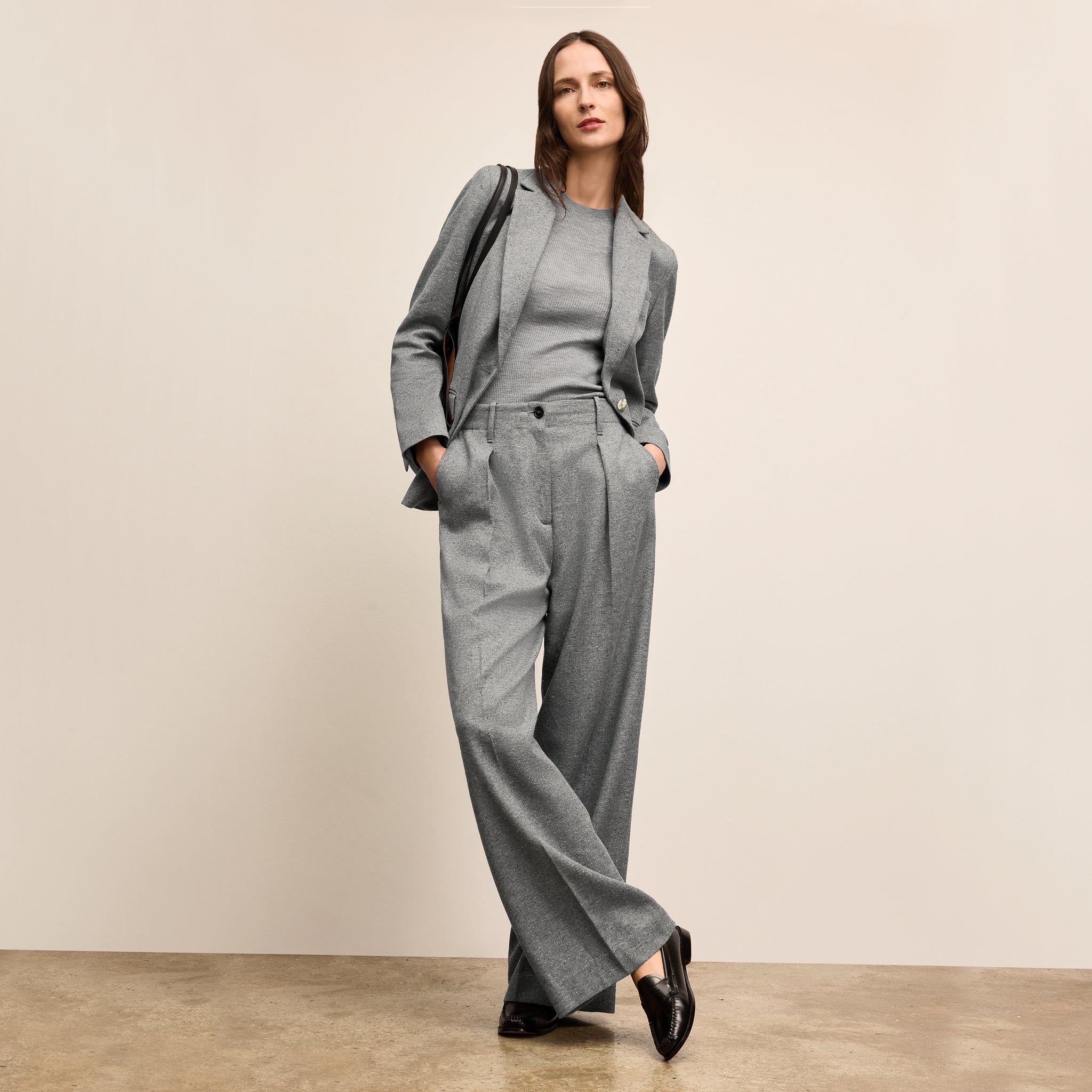 Woman wearing a gray suit with a beige background