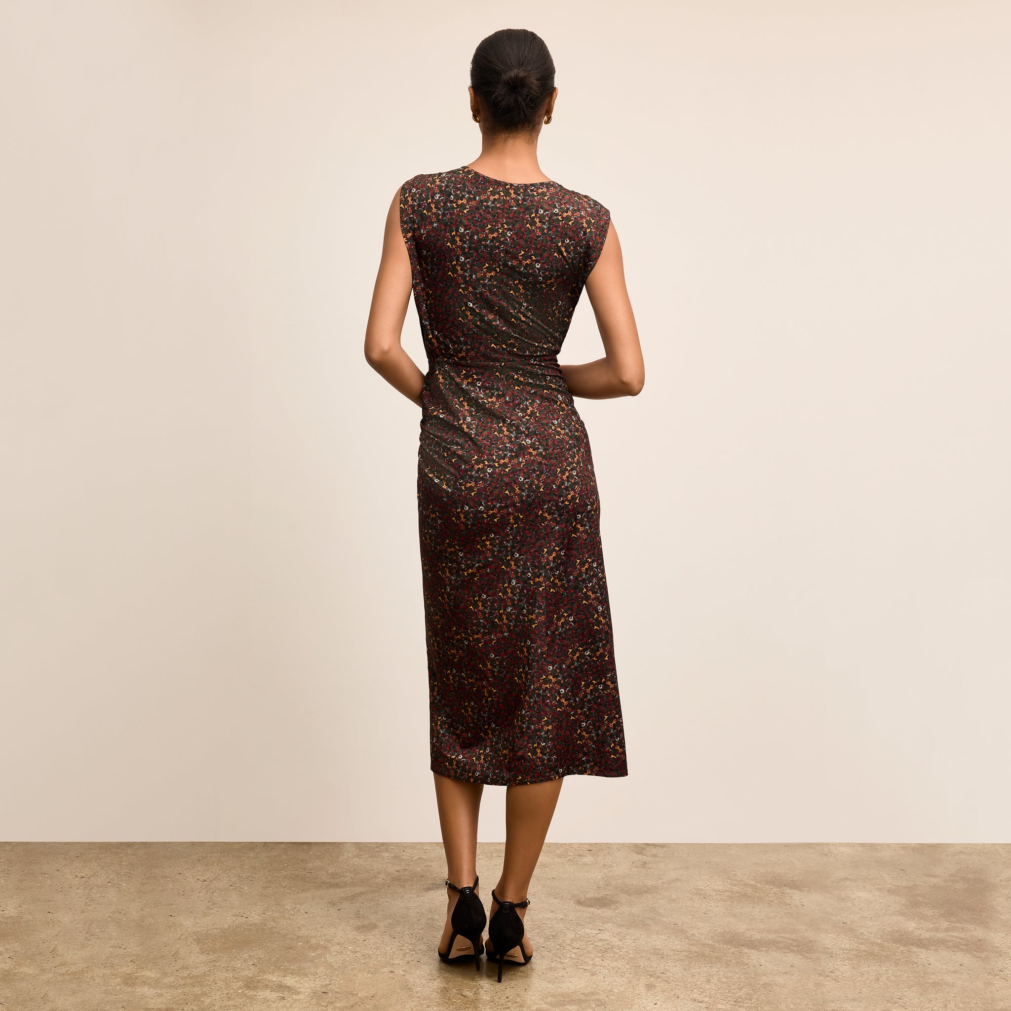 Woman wearing a patterned dress standing against a plain background