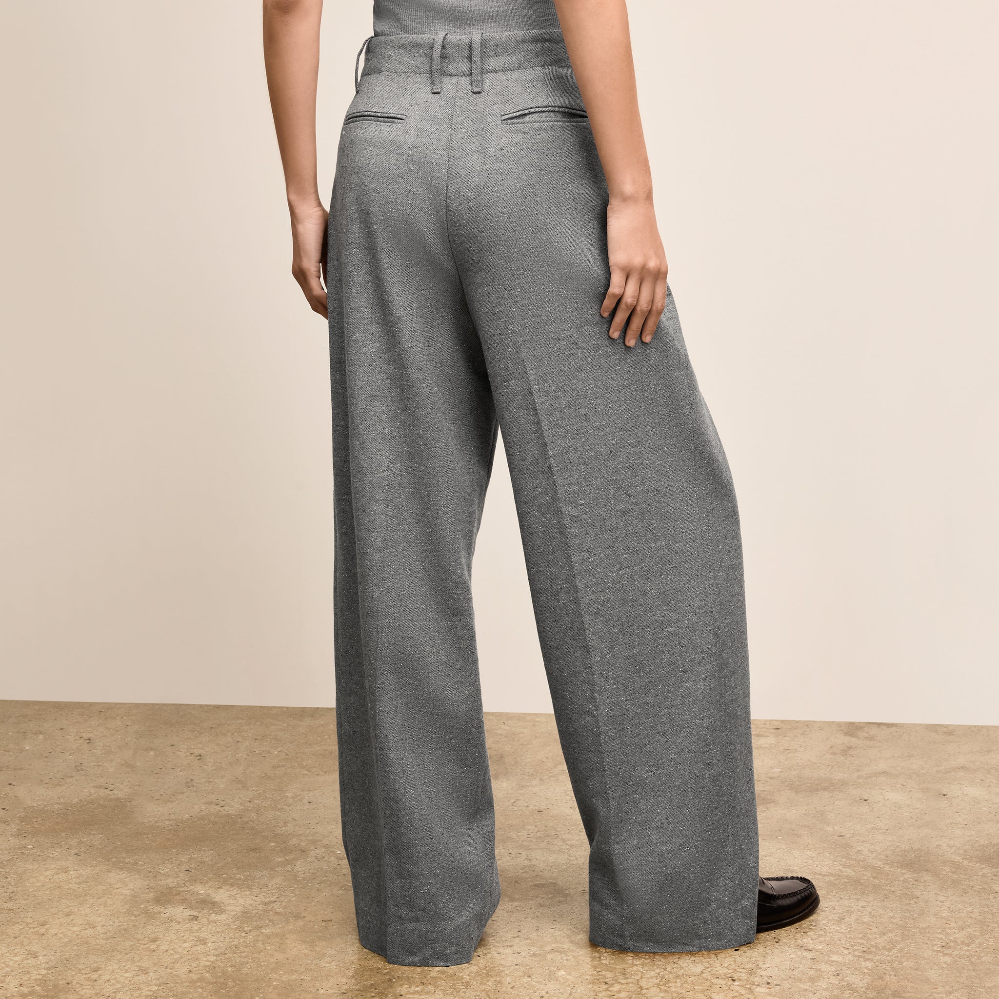 Person wearing gray wide-leg pants on a beige background