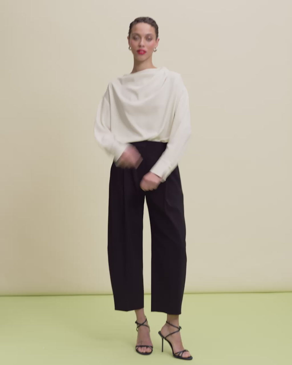 video of a woman wearing an ivory top and black pants