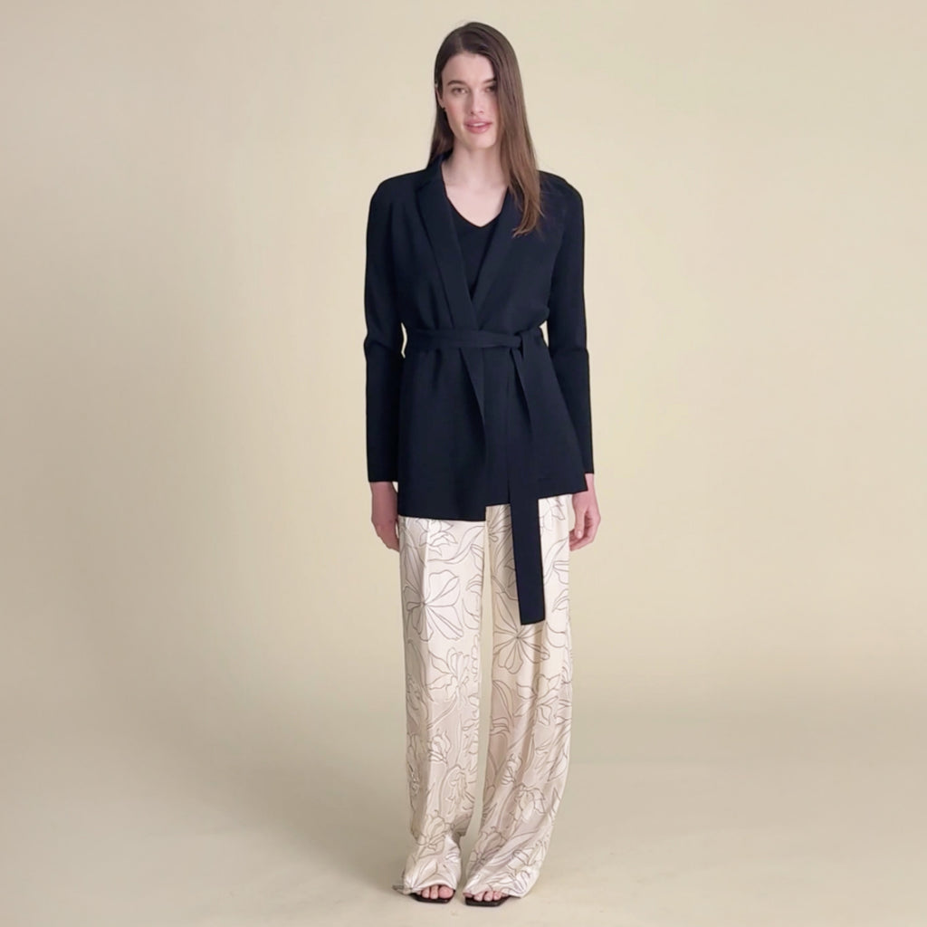 woman in black jardigan and white satin pants.