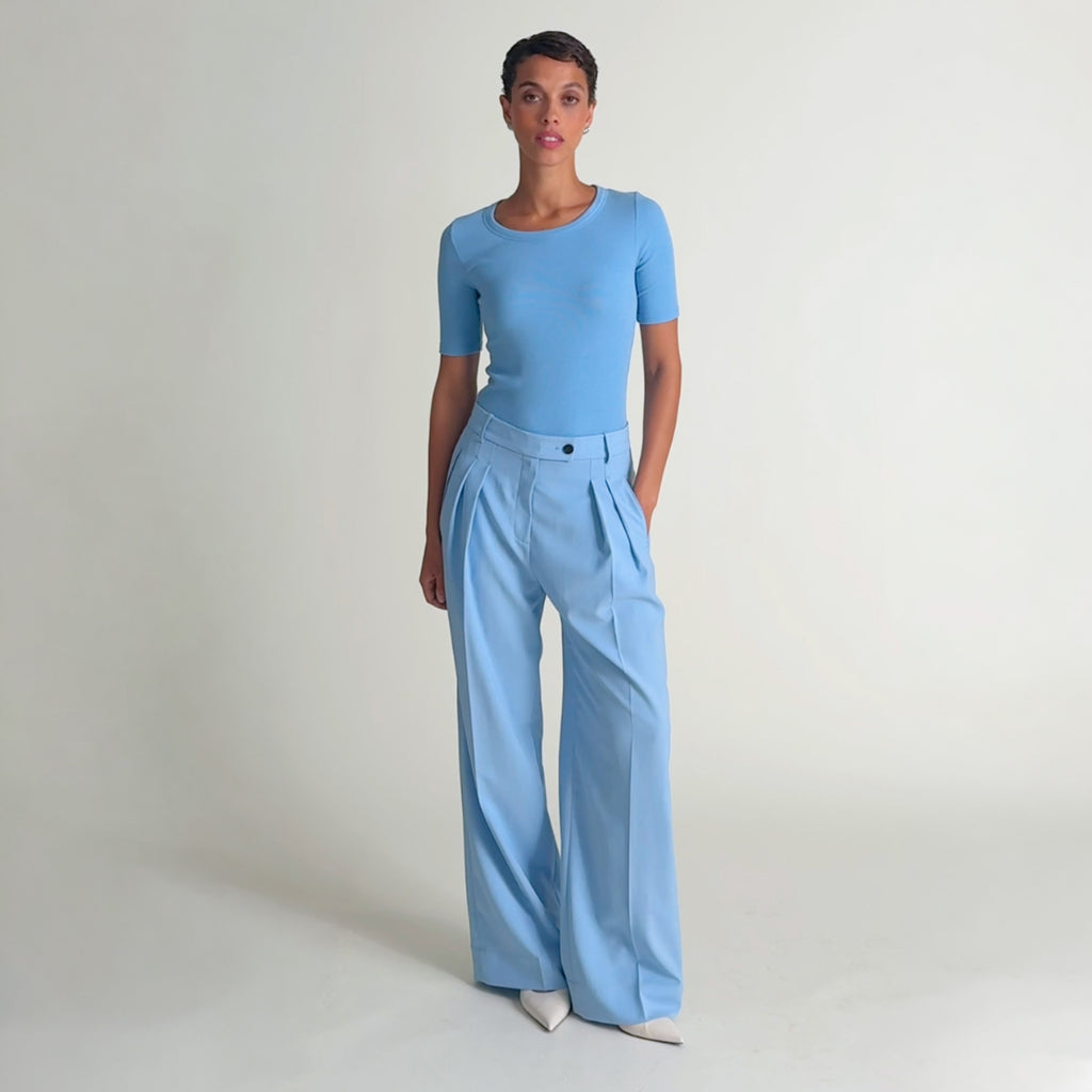 Video of a woman wearing a crew neck, short sleeve t-shirt with light blue trouser pants