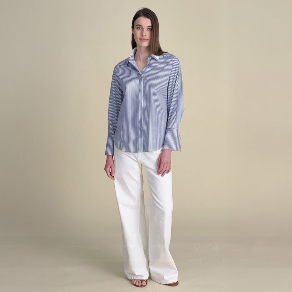 woman in striped button down with white pants.
