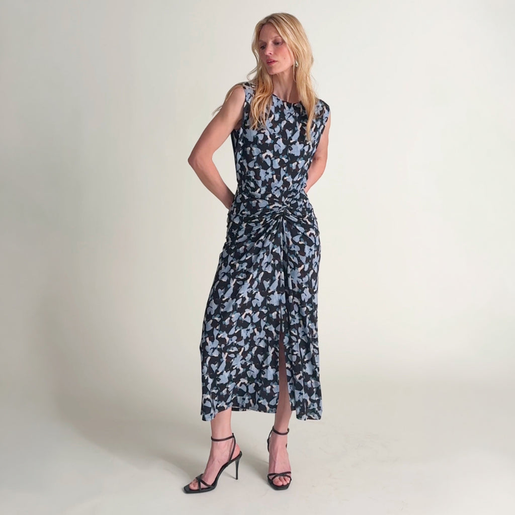 Video of a woman wearing a patterned navy and light blue printed sleeveless midi dress 