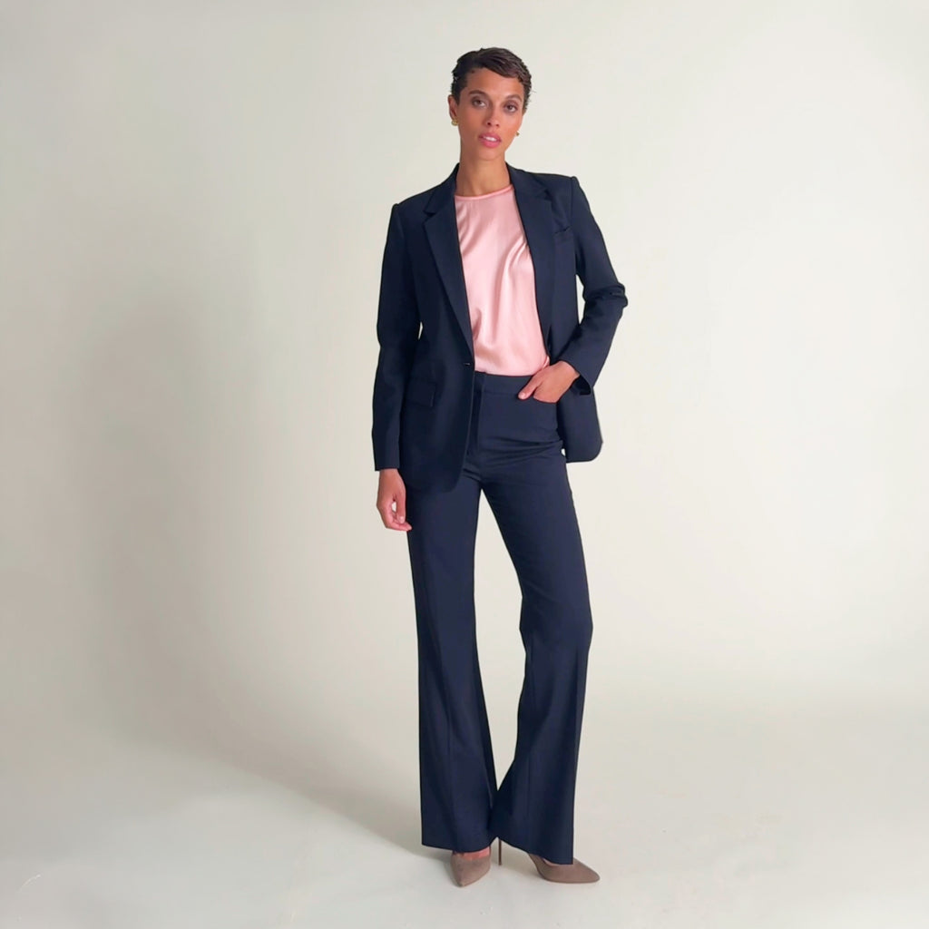 Woman wearing the didion top in petal pink wtih the yiyan blazer and horton pant in dark navy
