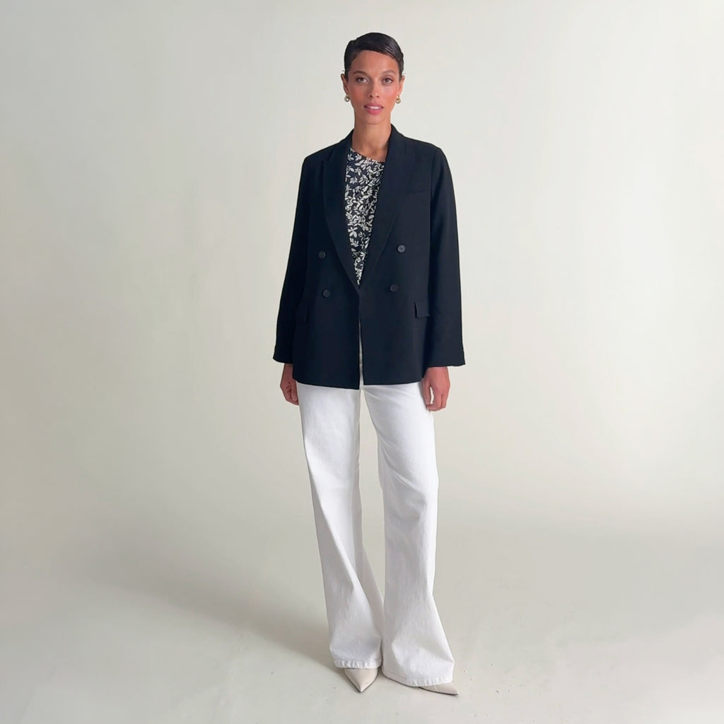 Woman wearing the hera top in leaf line fern, white jeans, and the o'hara blazer in oxford