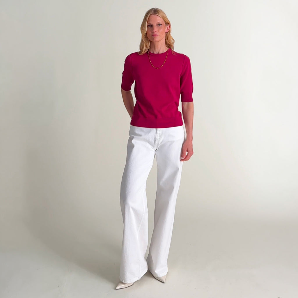 Woman wearing the iroha sweater in red raspberry and white jeans