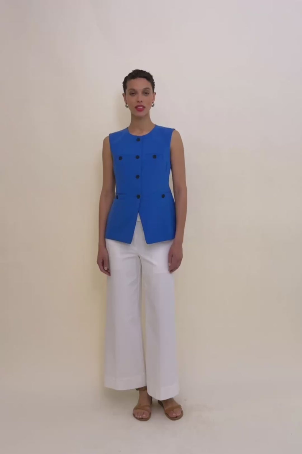 Woman wearing a blue vest with black buttons on a beige background 