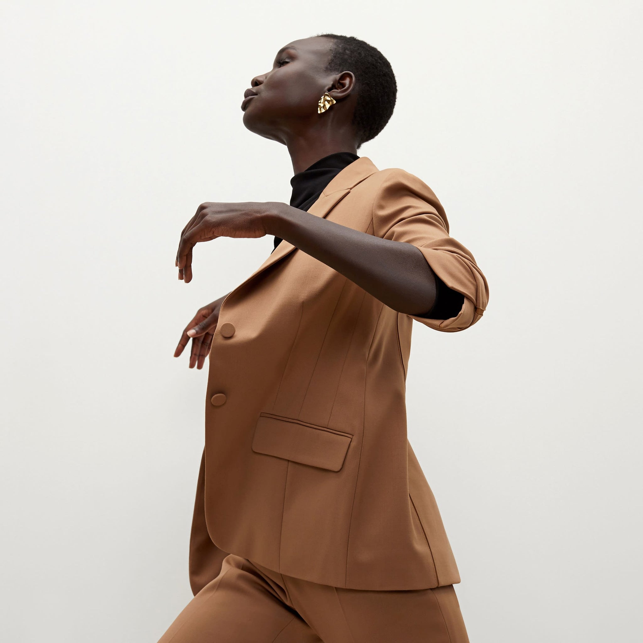 Side image of a woman standing wearing the bennett blazer wool twill in camel