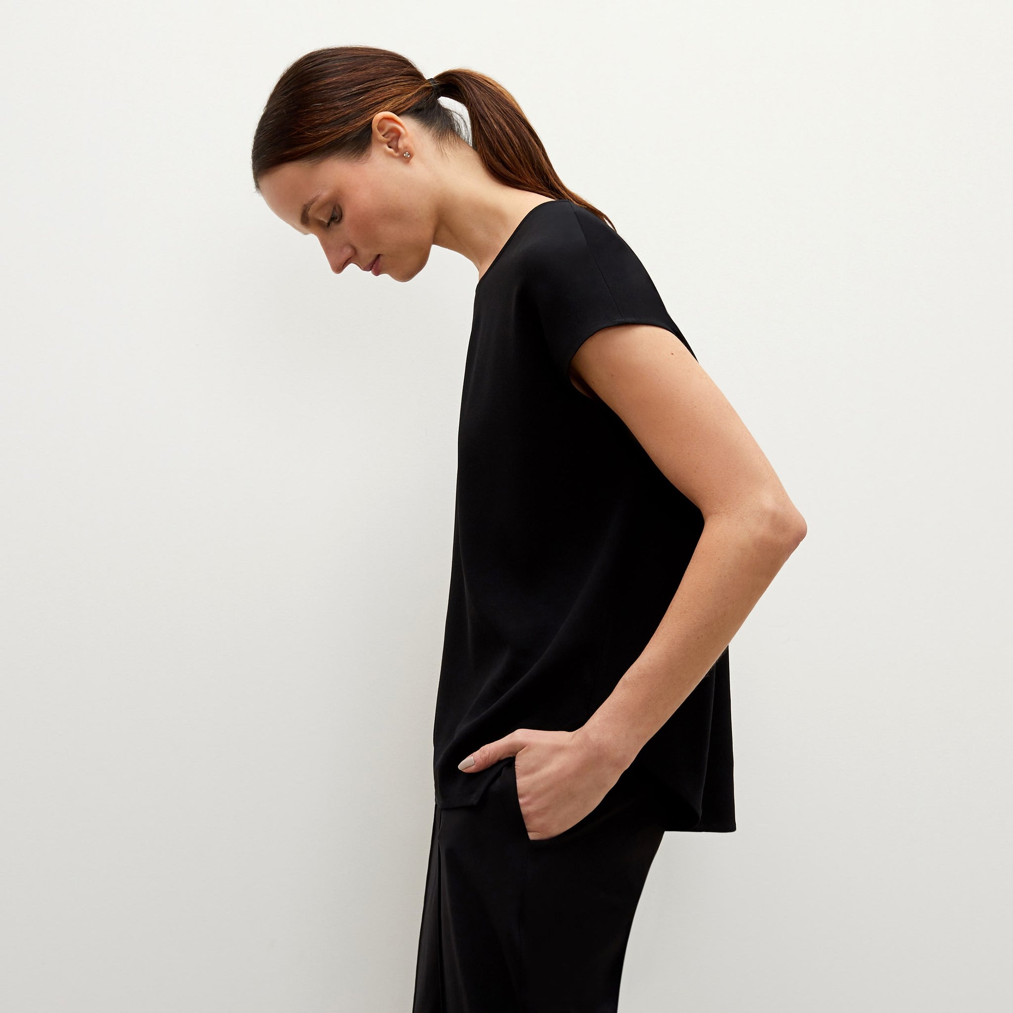 Side image of a woman standing wearing the Didion top in black