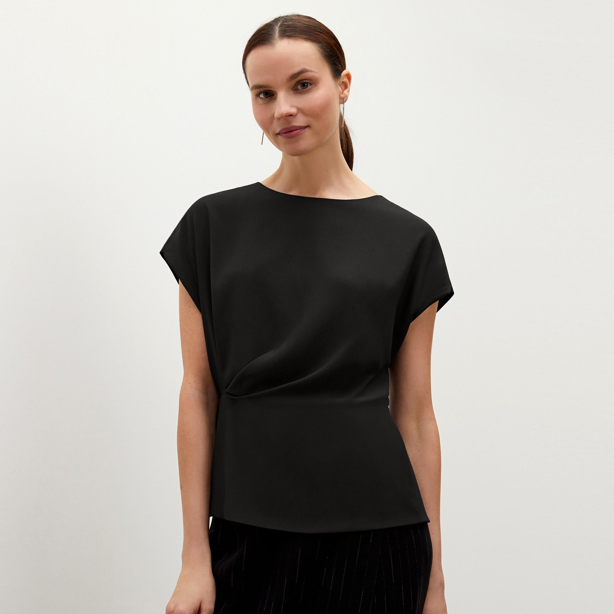 Front image of a woman standing wearing the Nejvi top in black