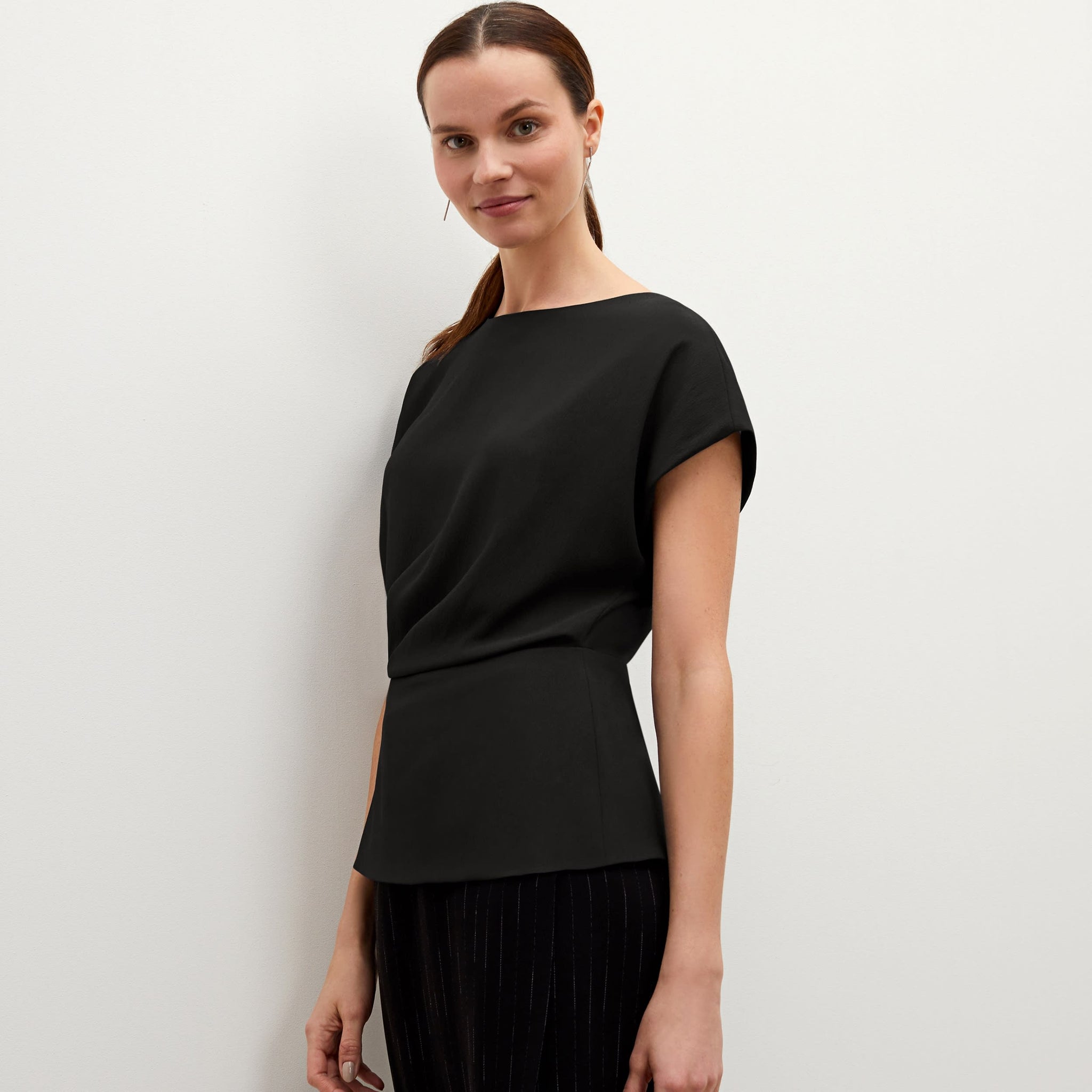 Front image of a woman standing wearing the Nejvi top in black