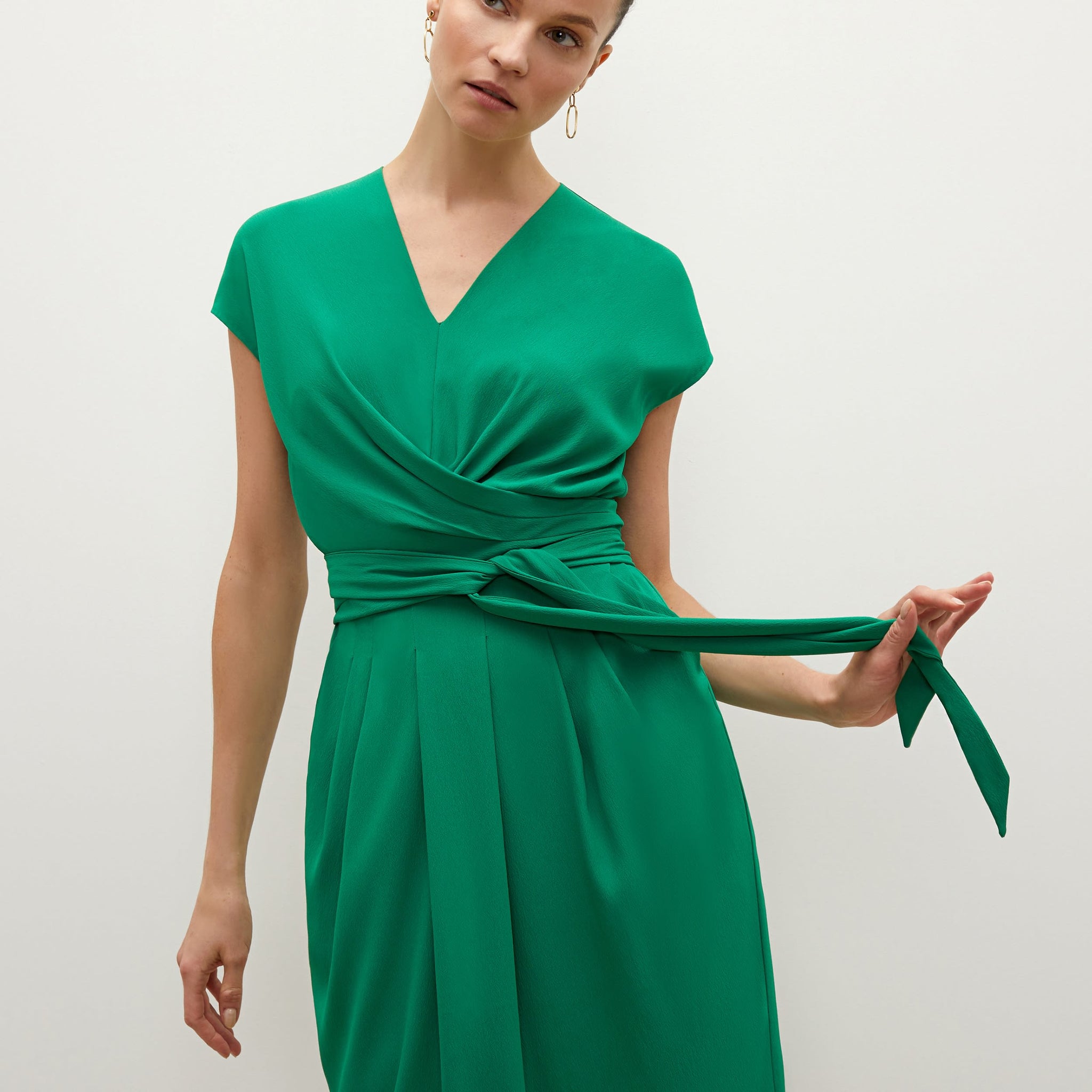 Side image of a woman standing wearing the Noel dress in emerald