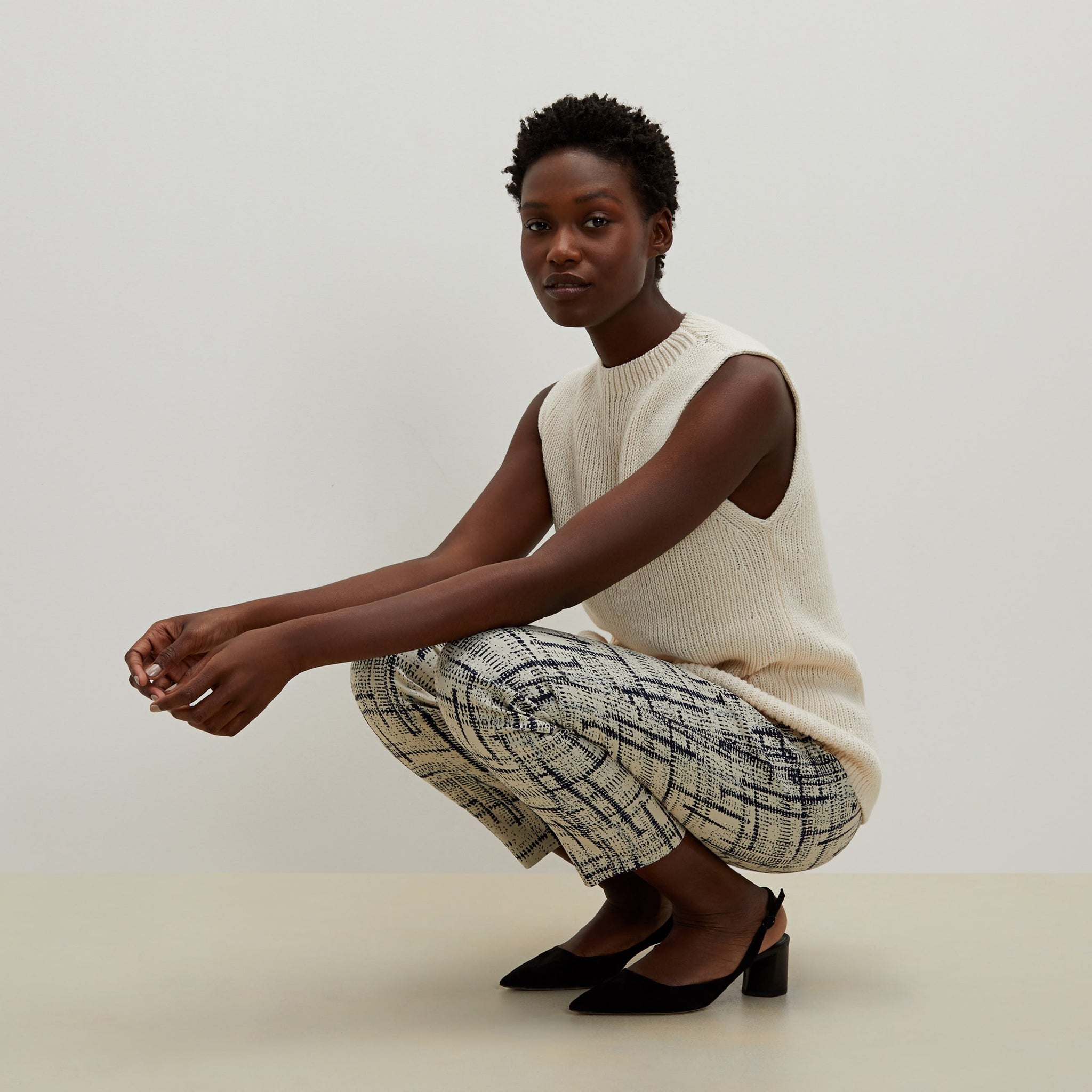 Side image of a woman standing wearing the Spardel top in ivory