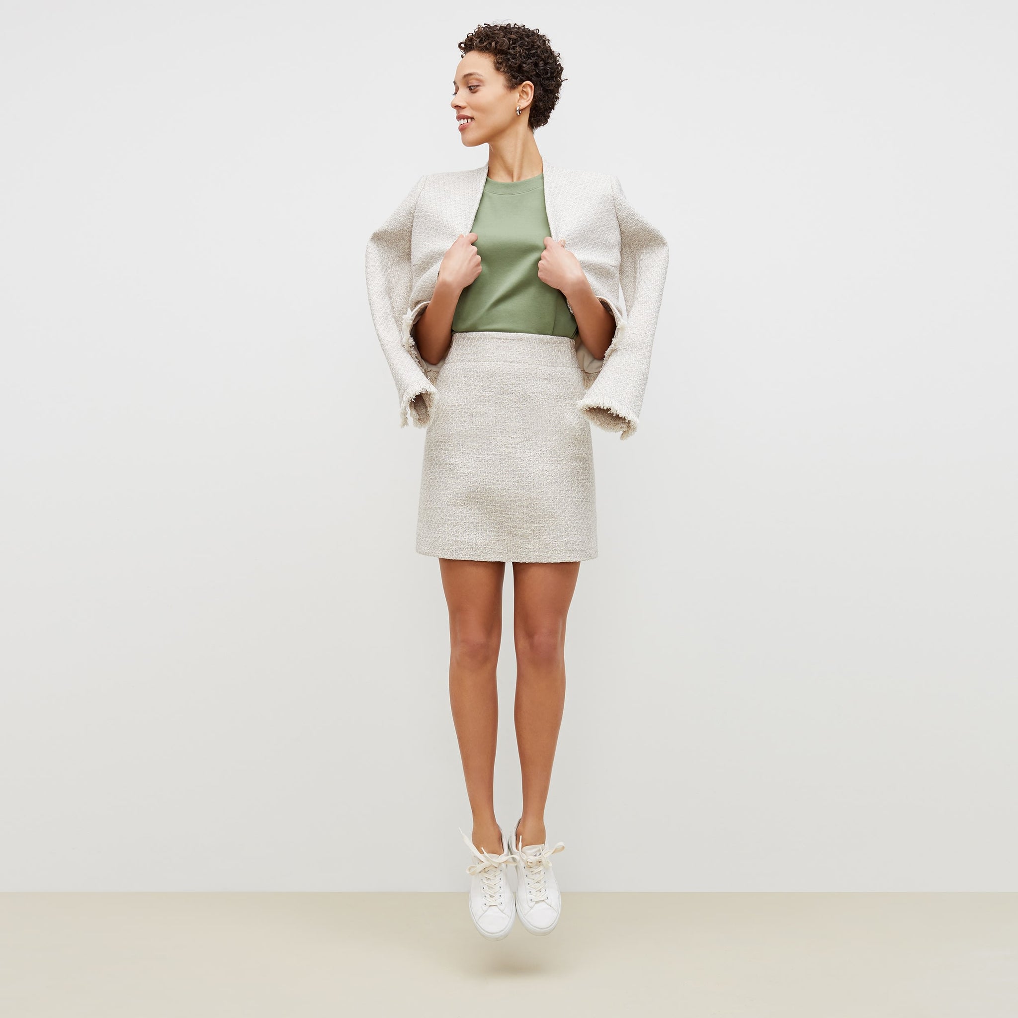 Front image of a woman standing wearing the rowley skirt cotton boucle in sea salt / ivory