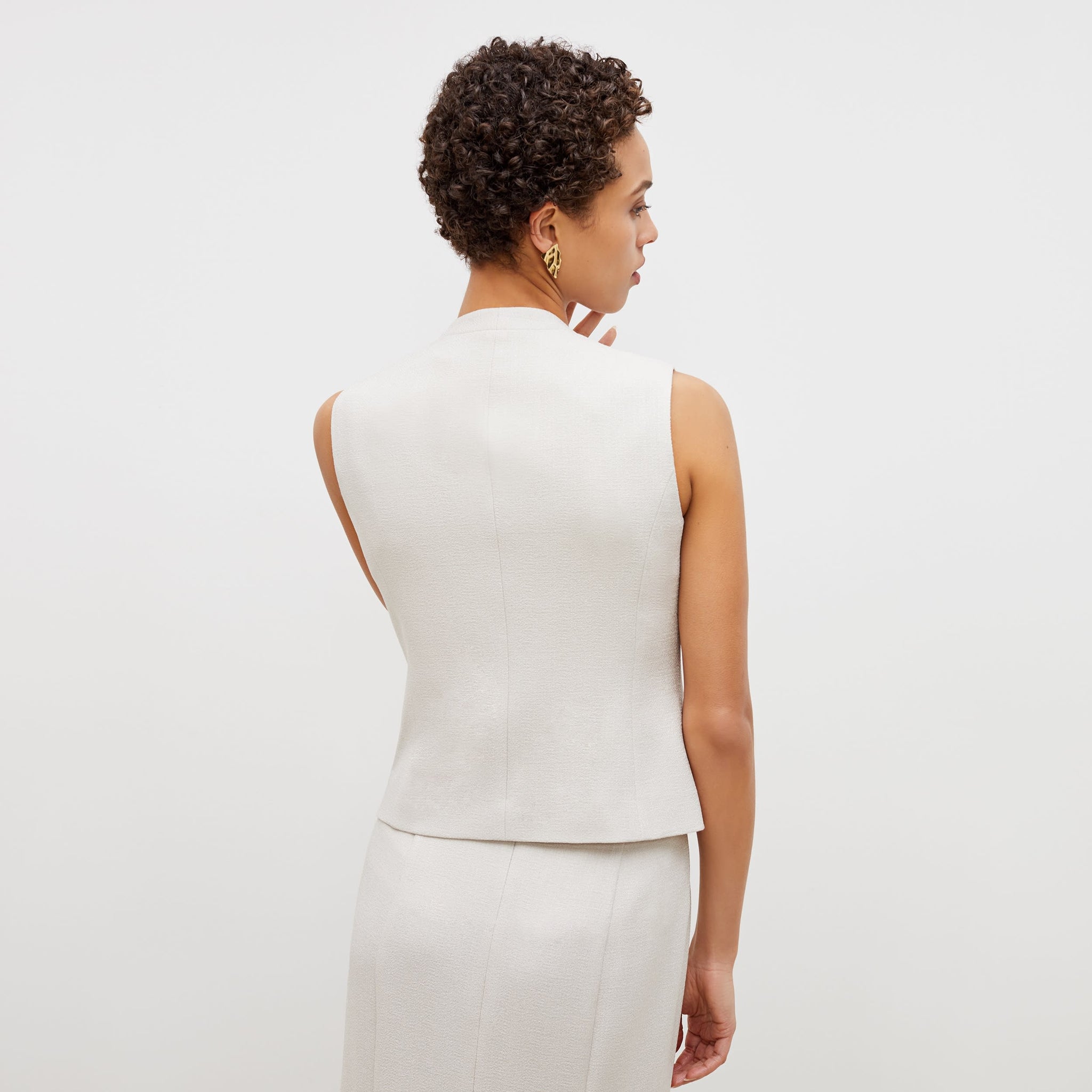 Back image of a woman standing wearing the willow vest in textured suiting in magnolia