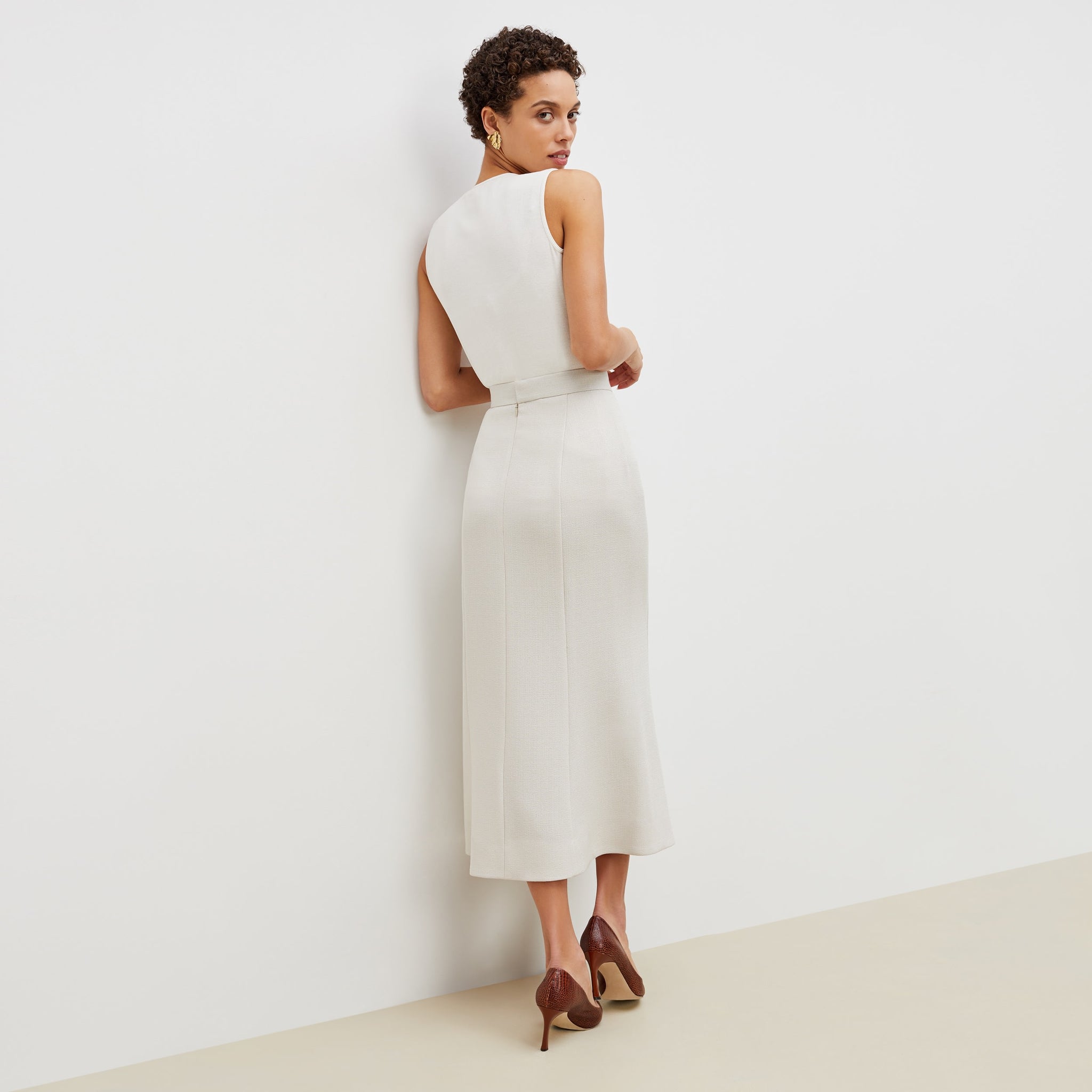 Back image of a woman standing wearing the eva skirt in textured suiting in magnolia
