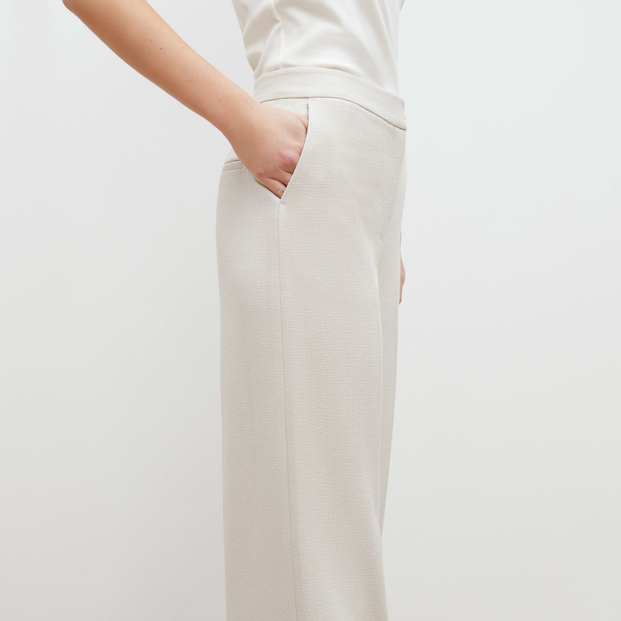 Side image of a woman standing wearing the anderson pant in textured suiting in magnolia