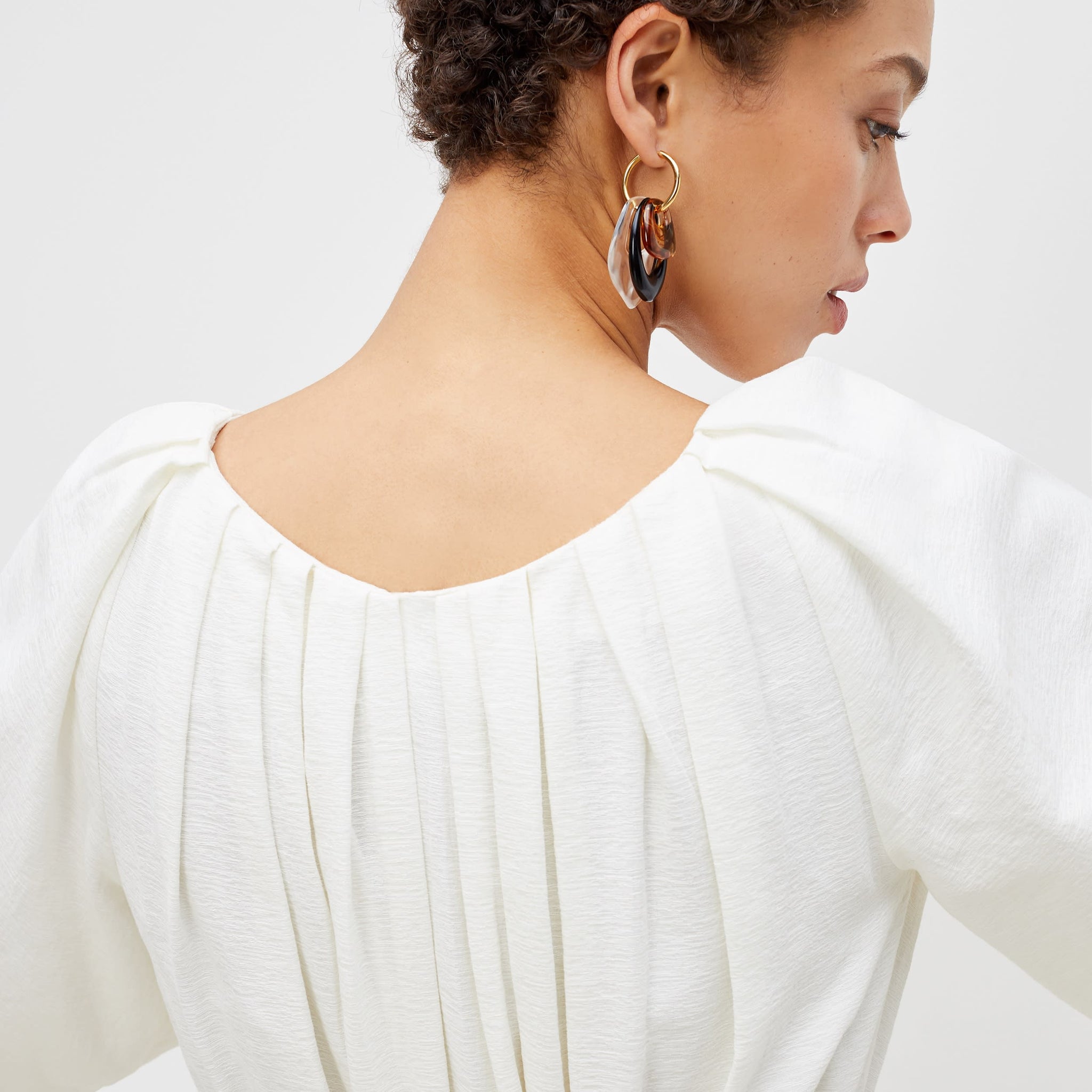 Back image of a woman standing wearing the medina dress in textured voile in ivory